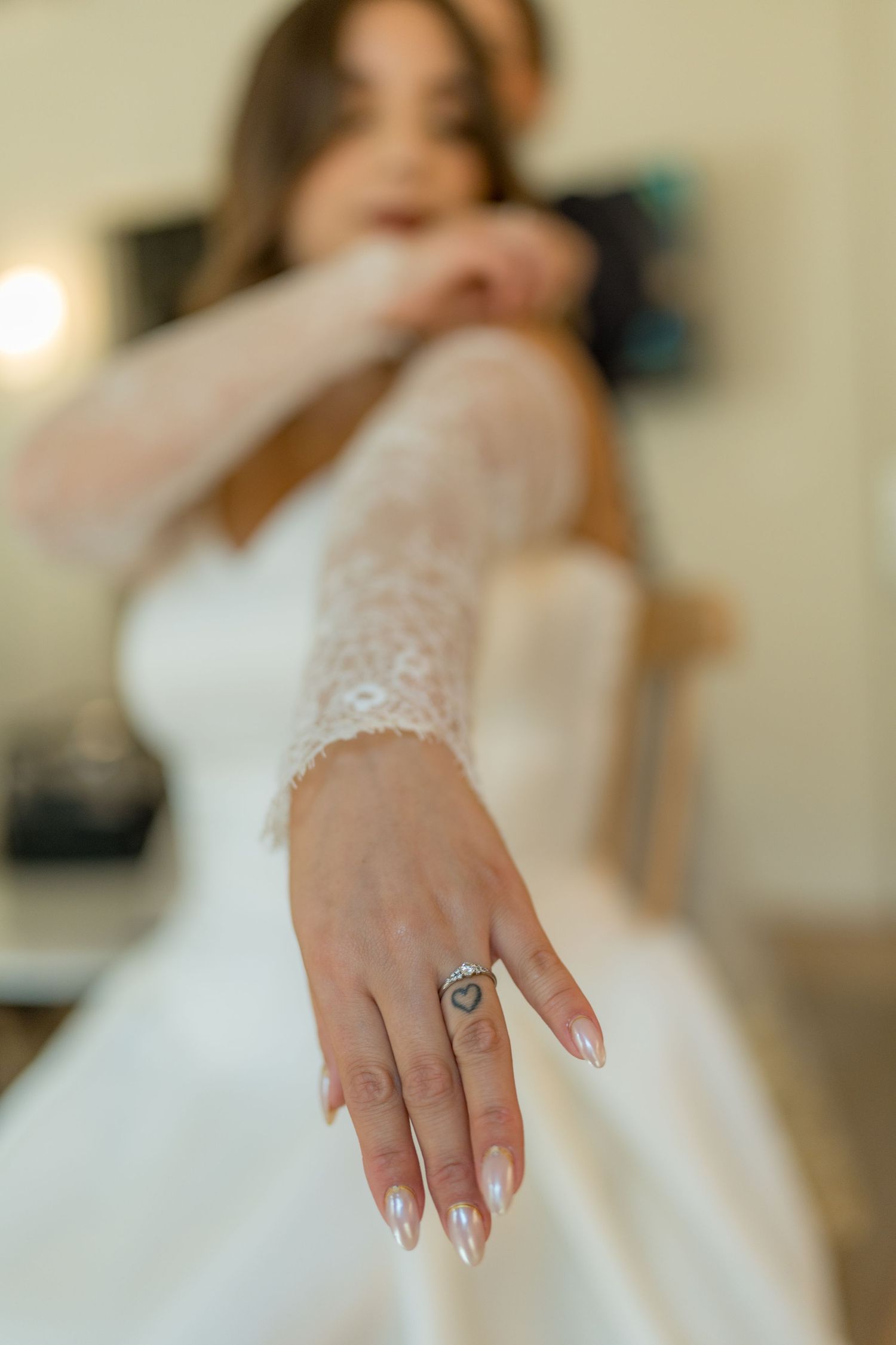 Bride in lace wedding dress showcasing her engagement ring with French manicure.