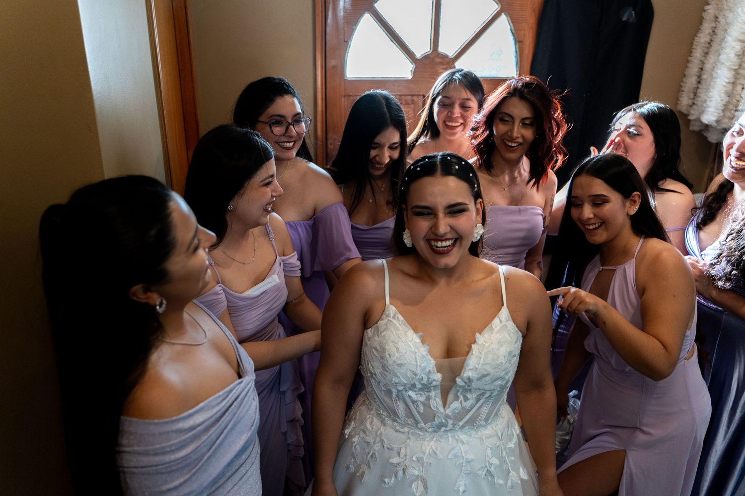 Wedding party shares joyful moments in an indoor venue with natural lighting.