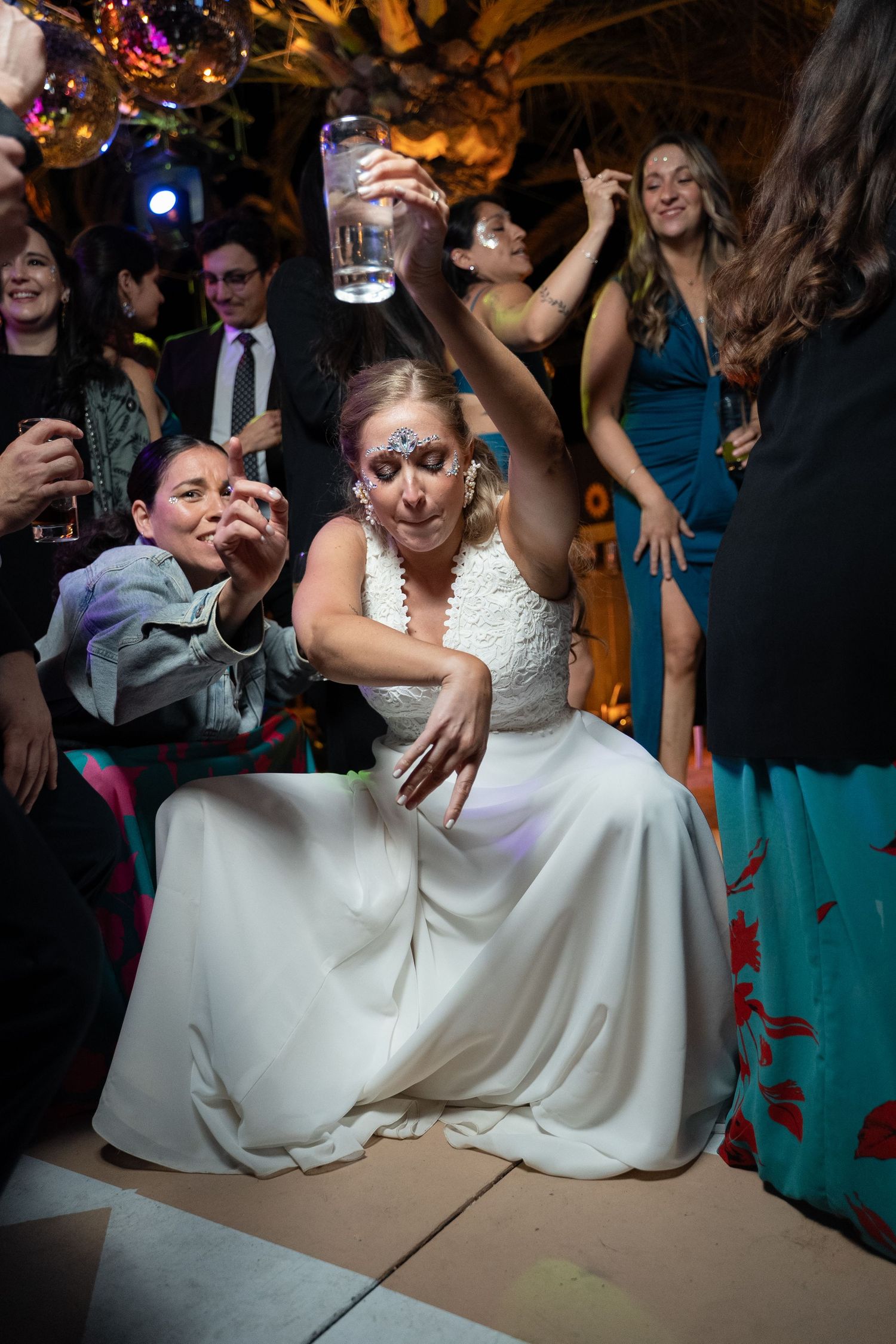 Bride in white dress dances energetically during wedding reception party.