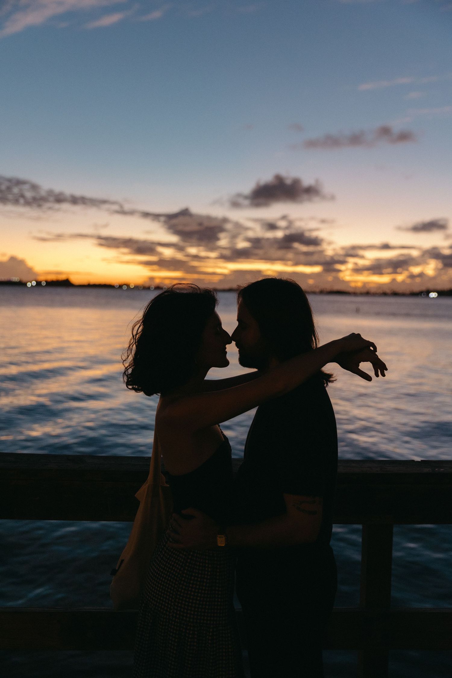 A romantic silhouette of a couple embracing on a pier during golden hour sunset over tranquil ocean waters in Puerto Rico