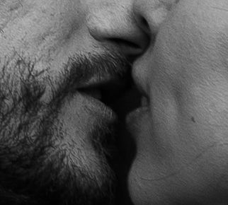 Intimate black and white close-up of couple sharing a romantic kiss.