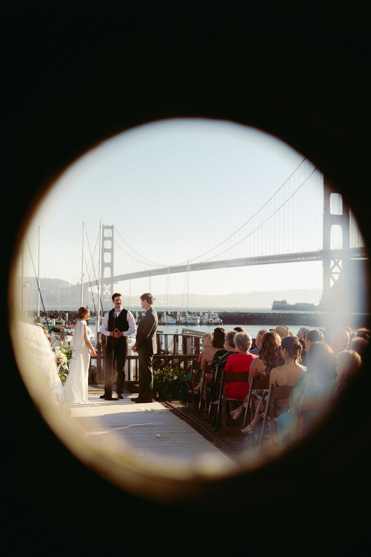 Wedding ceremony viewed through a porthole with the Golden Gate Bridge backdrop in San Francisco.