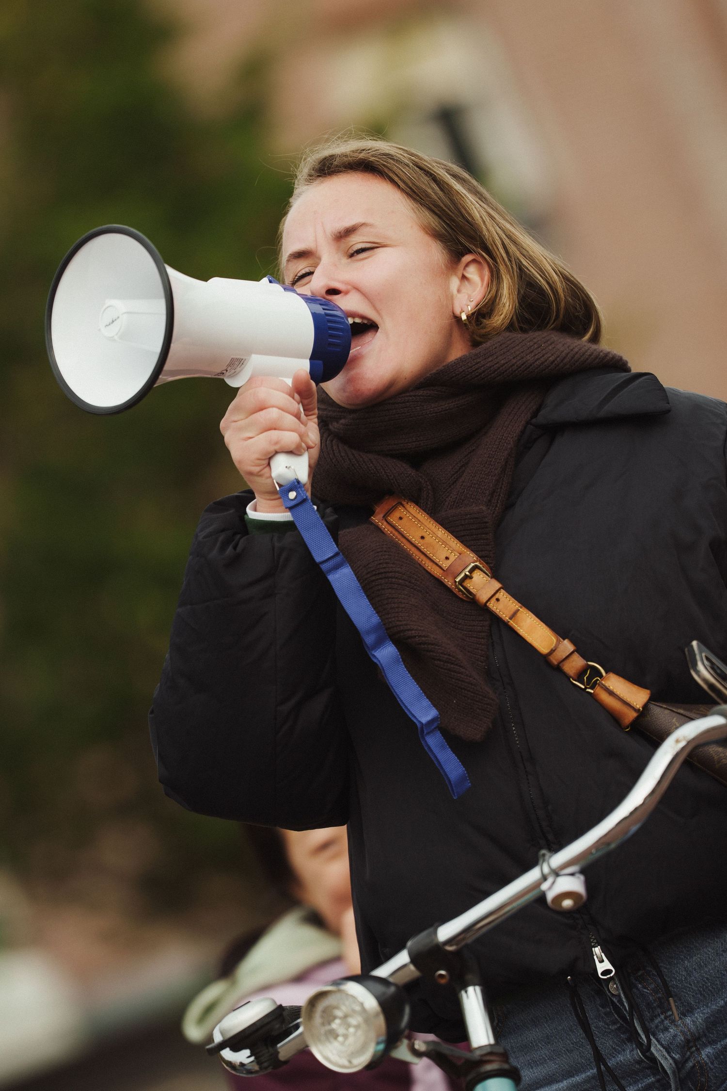 Person using a megaphone while standing with a bicycle.