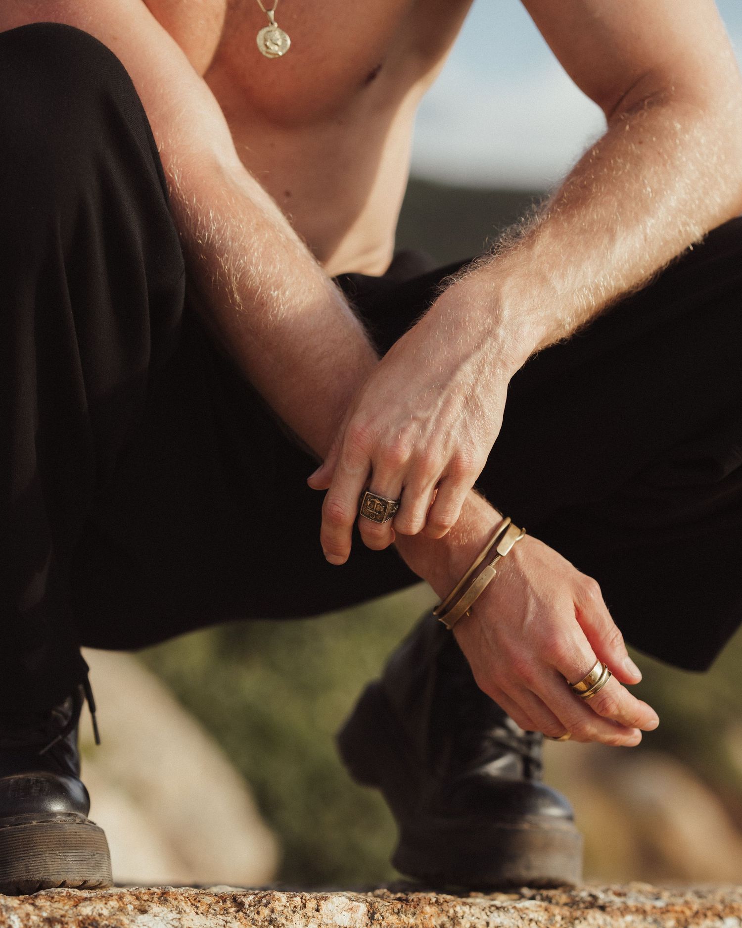 Hands reaching down to touch rocky surface in warm sunlight.