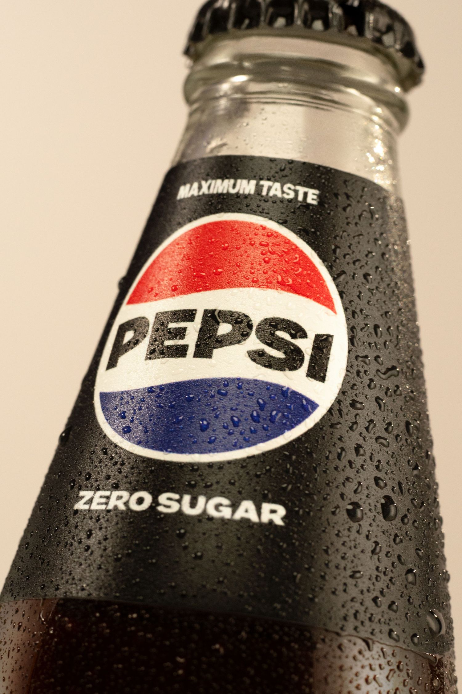 A chilled Pepsi Zero Sugar glass bottle with water droplets, featuring the classic red, white, and blue logo.