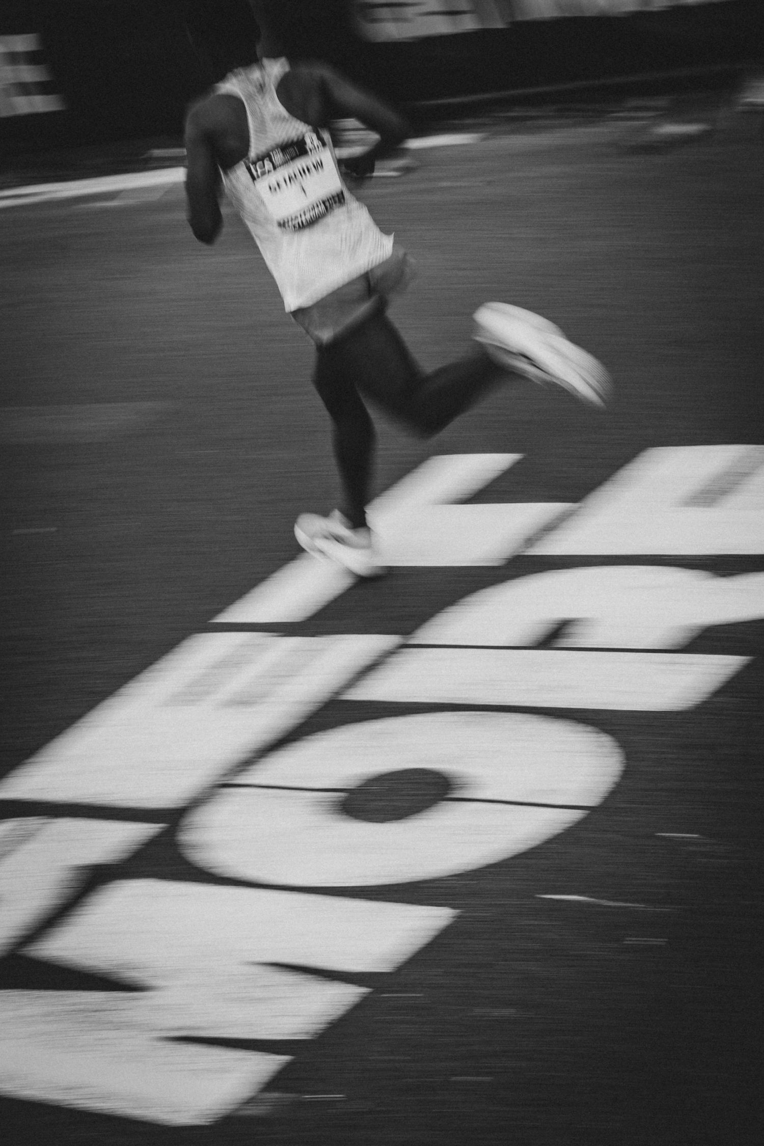 Motion-blurred runner passing over large text painted on race course.