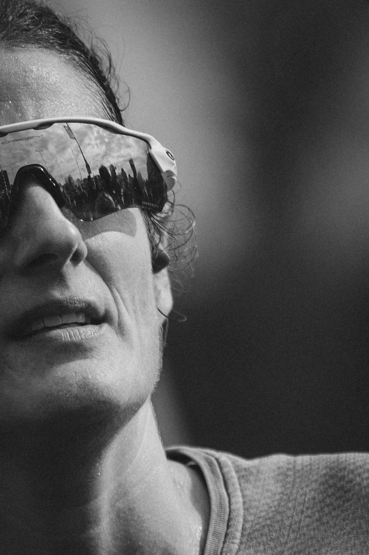 Close-up profile of runner wearing reflective sunglasses in black and white.