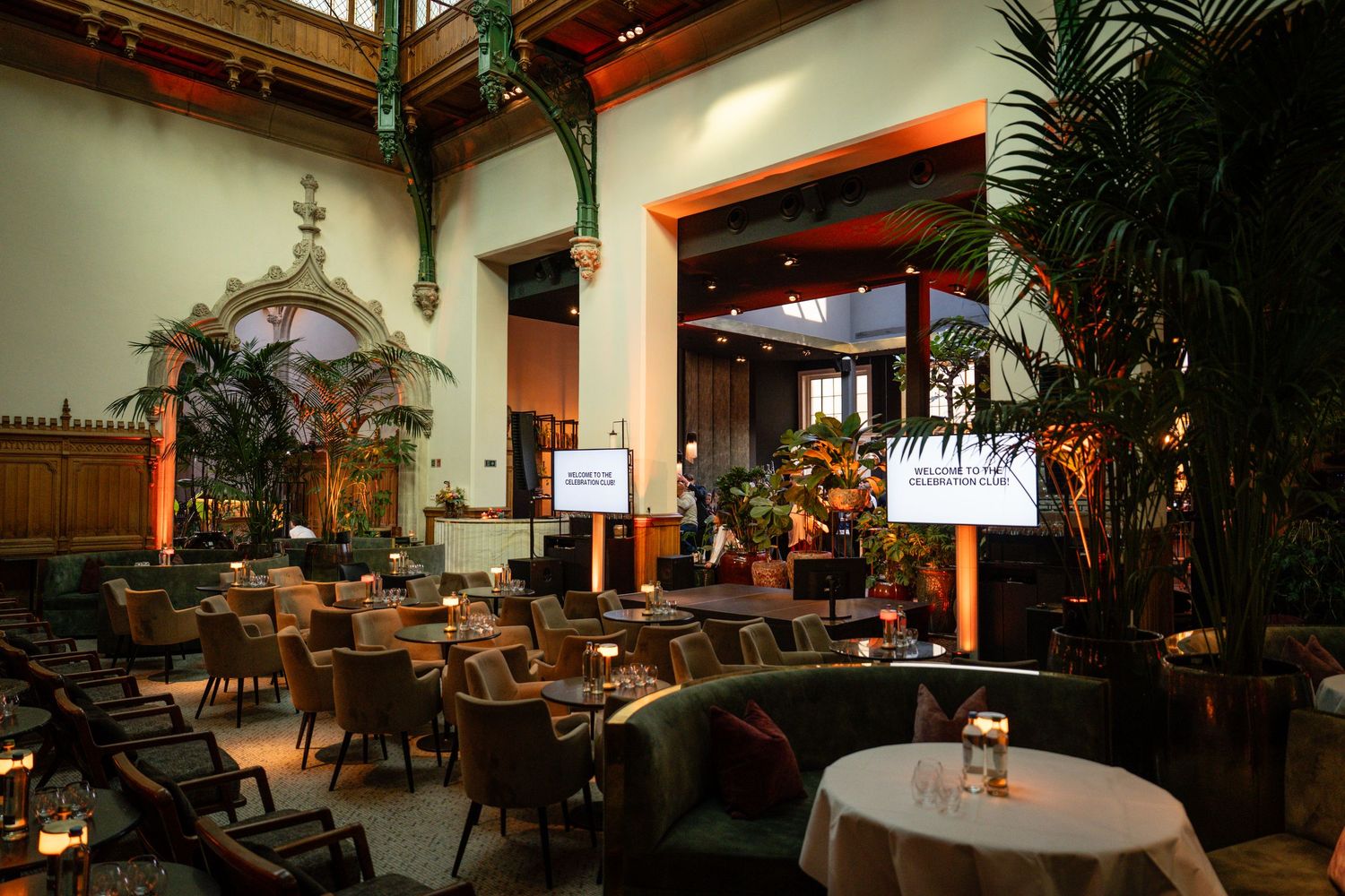 Interior view of an elegant restaurant with palm plants and ambient lighting.