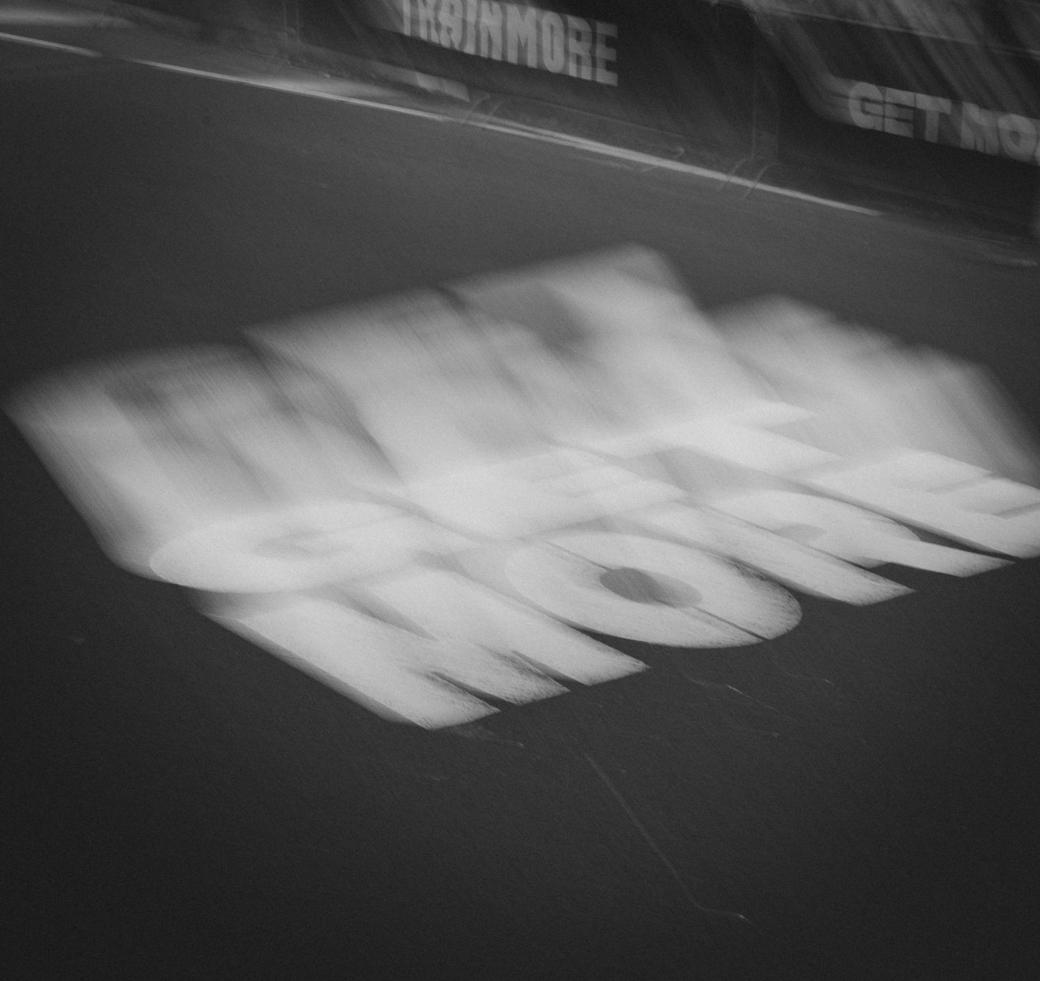 Black and white motion blur of text on asphalt during a marathon race.