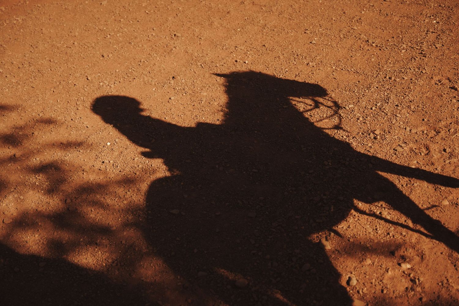 Long shadows cast on red desert sand during golden hour hiking adventure.
