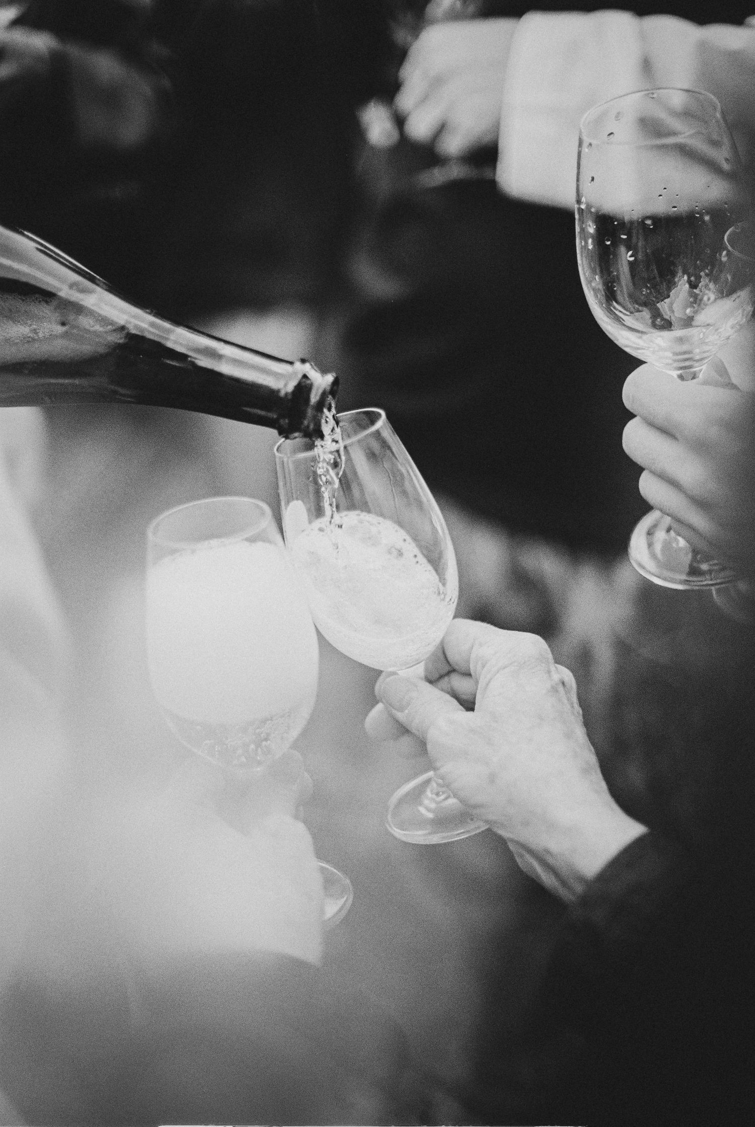 Black and white photo of champagne being poured into glasses at a celebration event.
