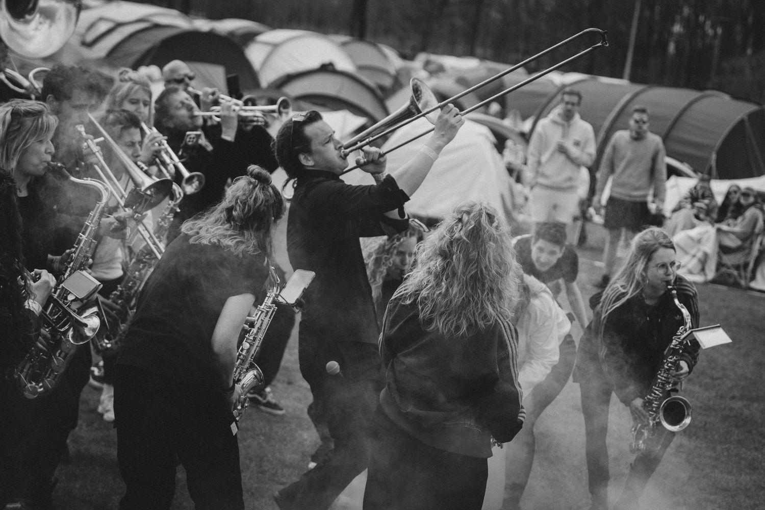 Black and white photo of a lively outdoor brass band performance with musicians playing trombones and saxophones.