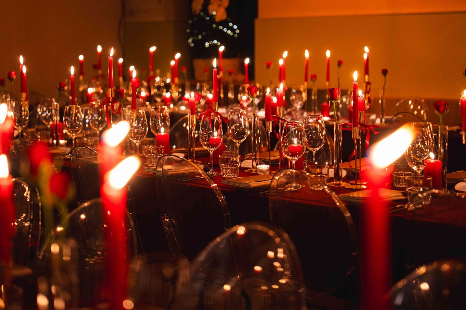 Elegant candlelit dinner table with red candles and crystal glasses creating a romantic atmosphere.