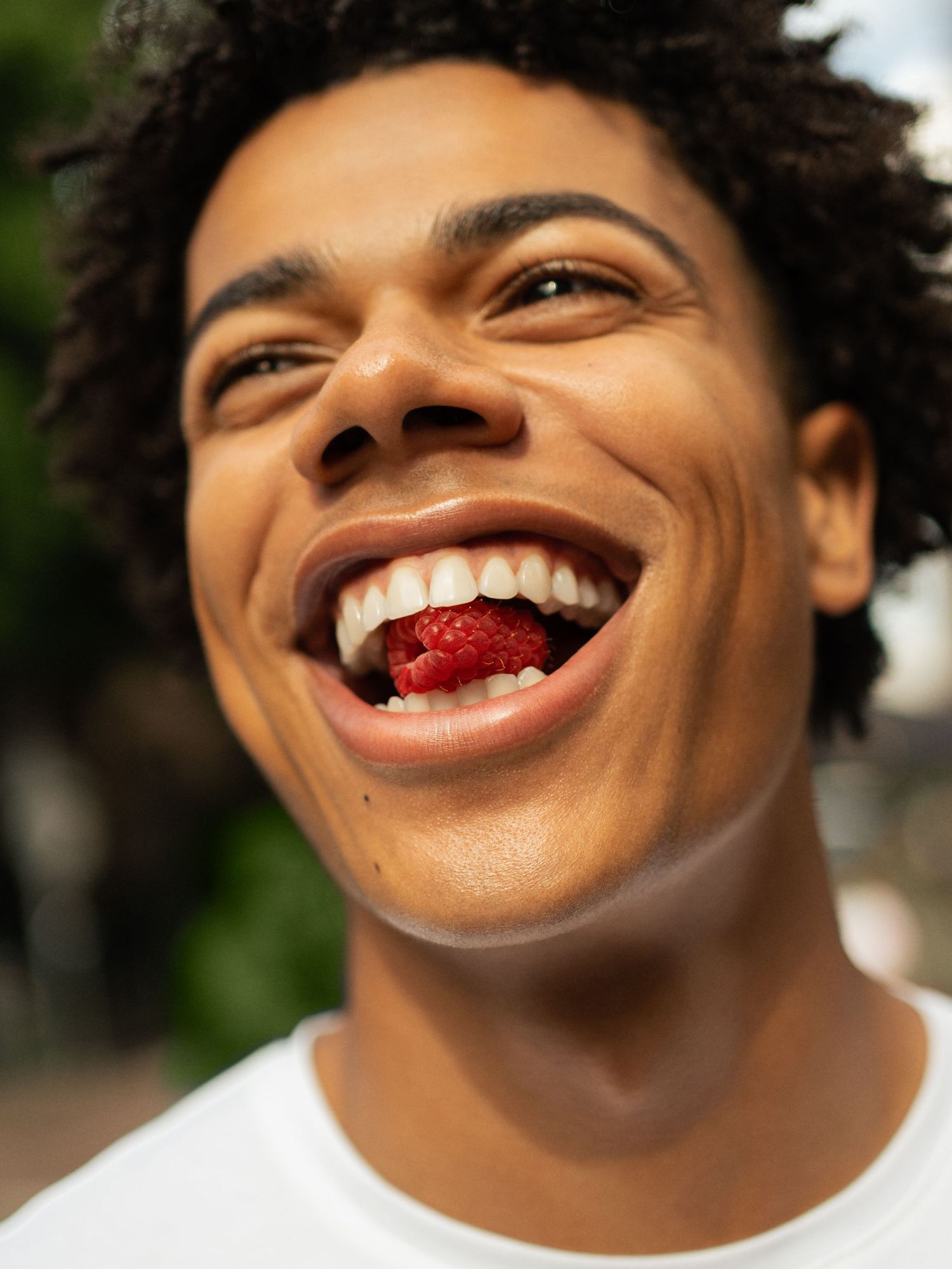 Happy young man smiling with raspberry in mouth outdoors.