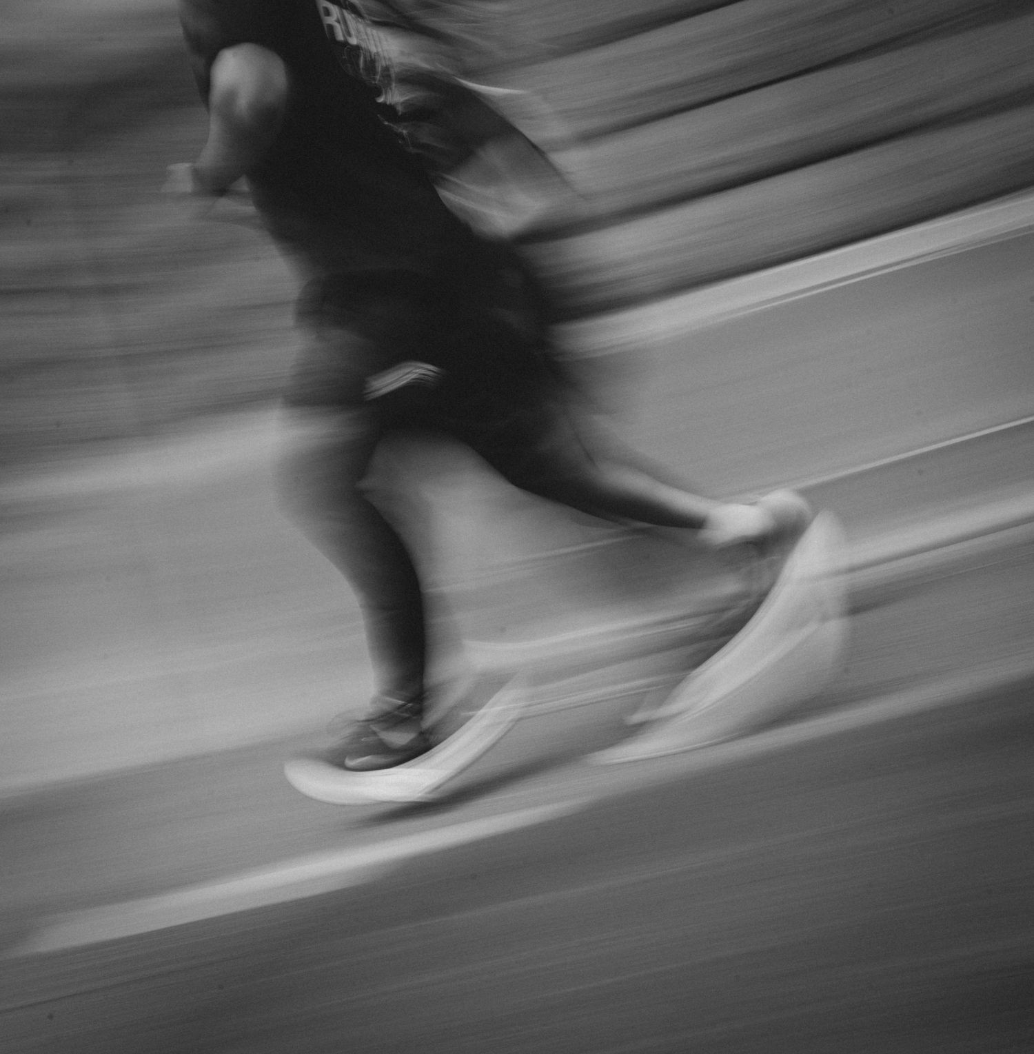 Black and white motion blur photo of a runner sprinting, capturing dynamic movement and athletic speed.