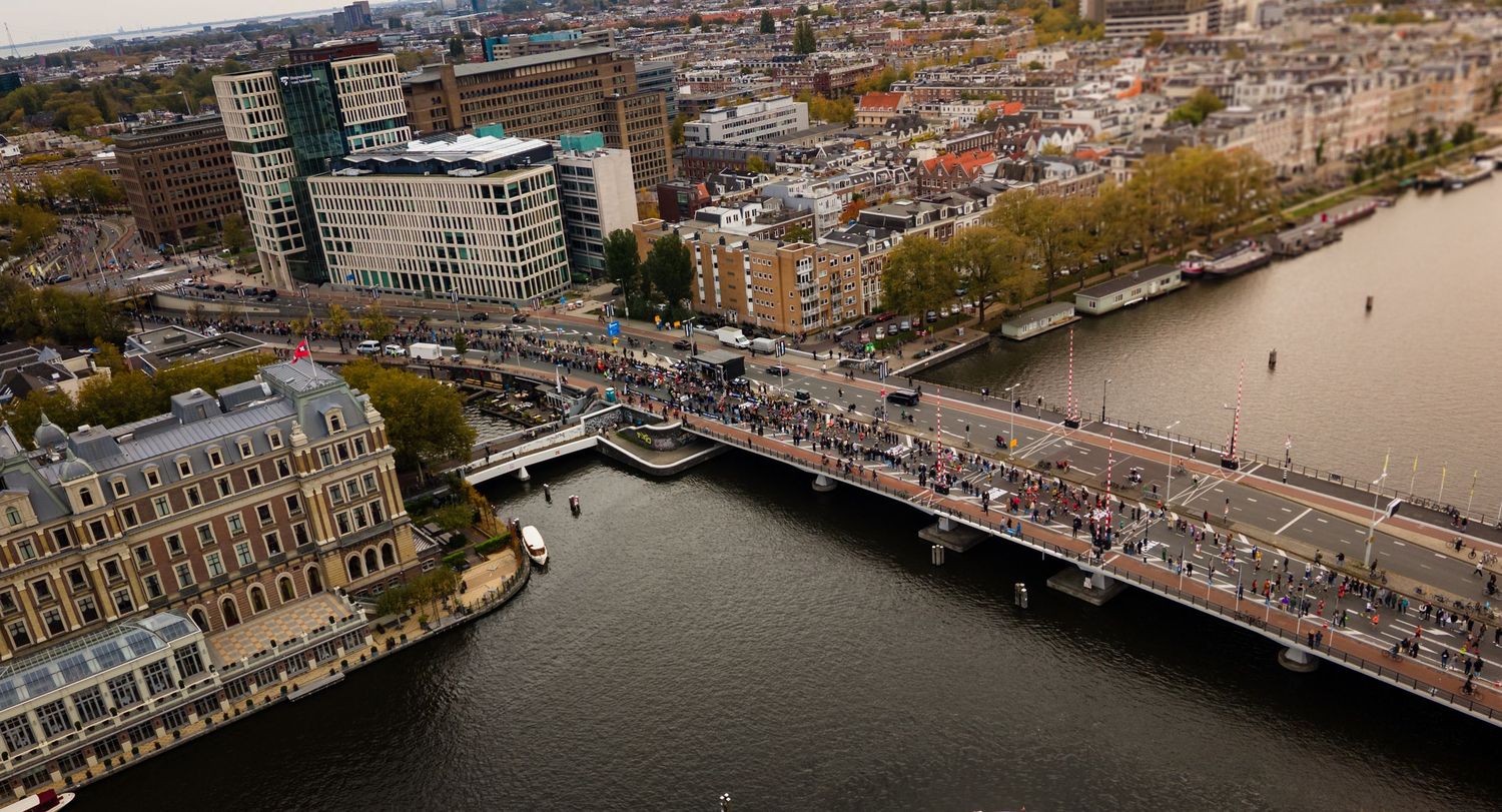 Bird's eye view of runners crossing a bridge over urban waterway.