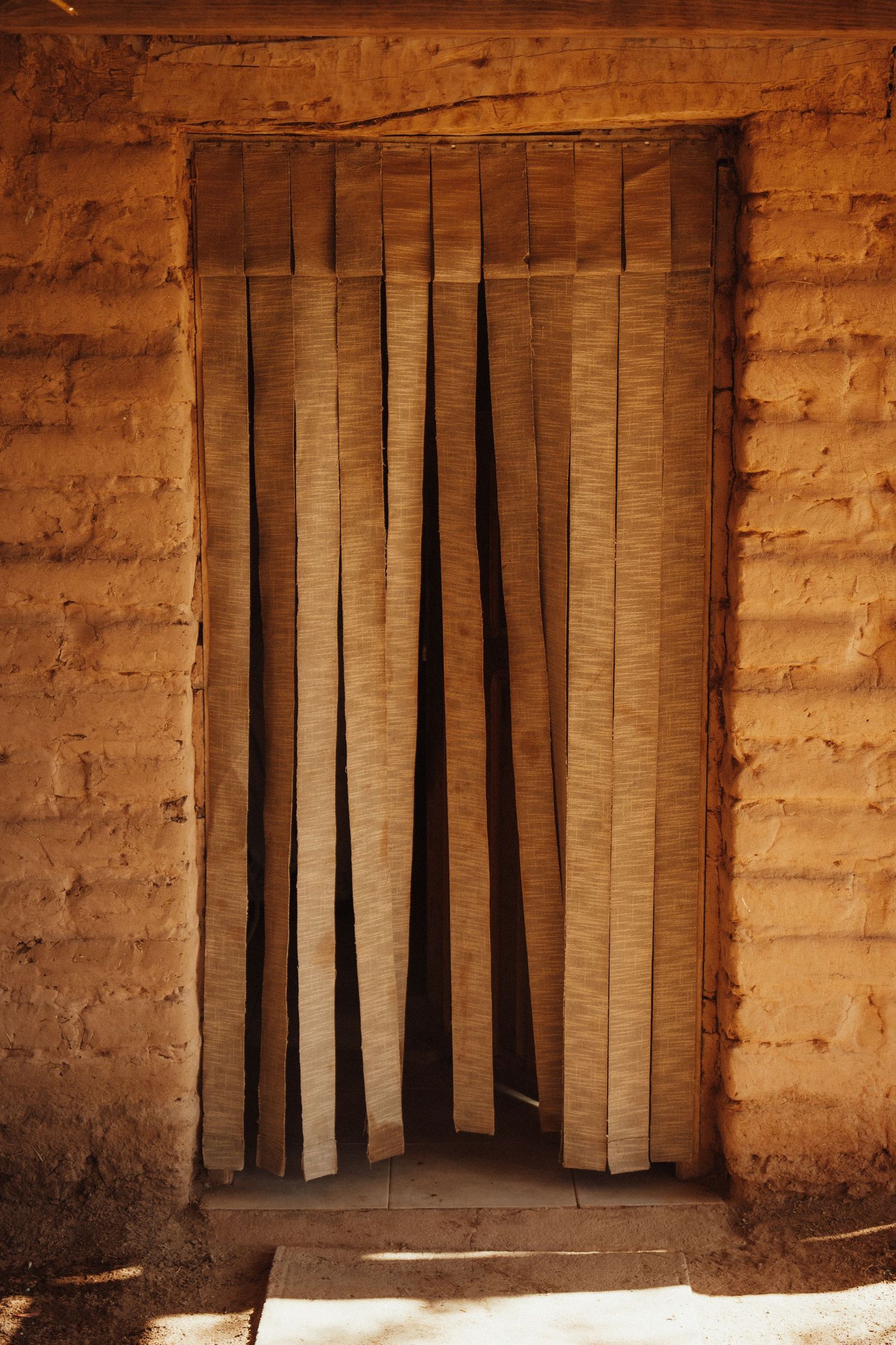 Interior view of adobe structure with vertical bamboo slat dividers.