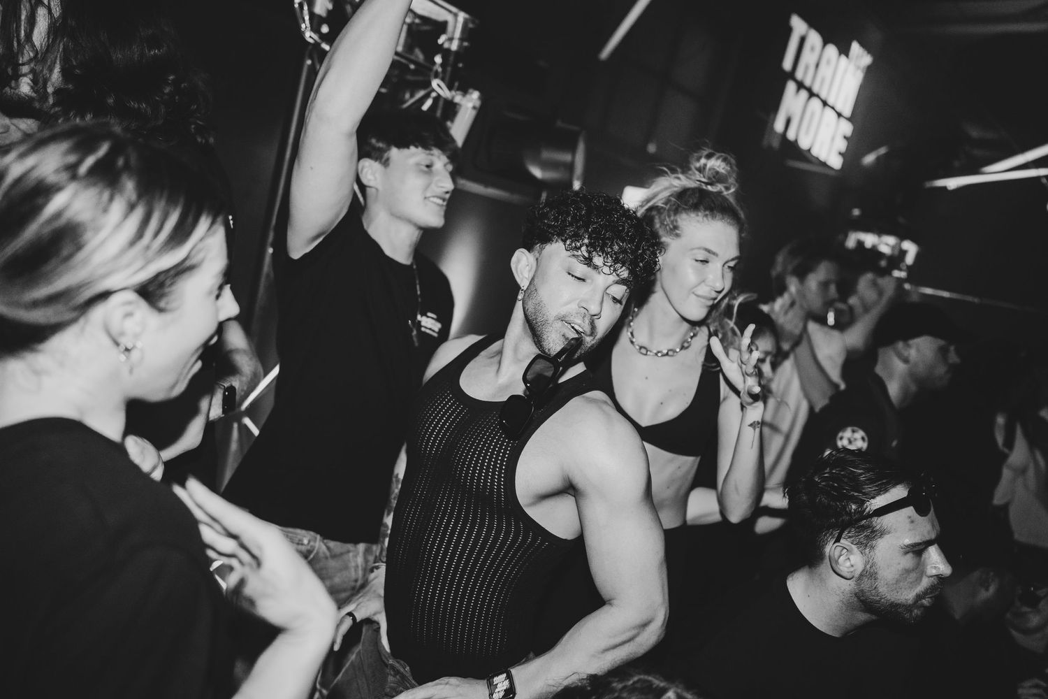 Black and white photo of people dancing closely together at a nightclub party event.