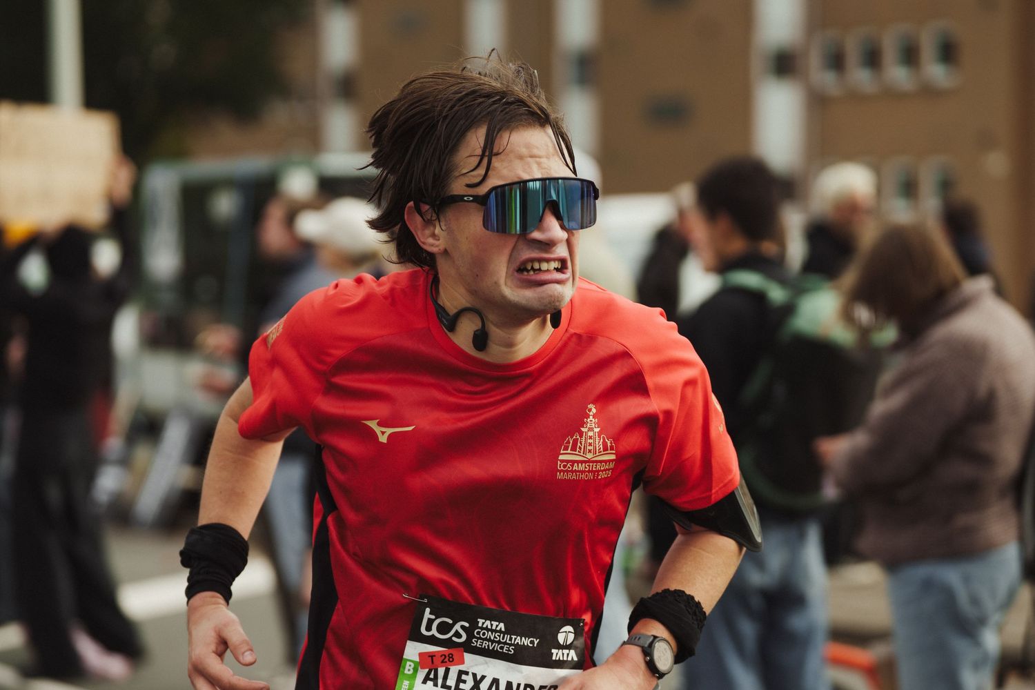 Runner in red jersey and sunglasses competing in Amsterdam marathon.