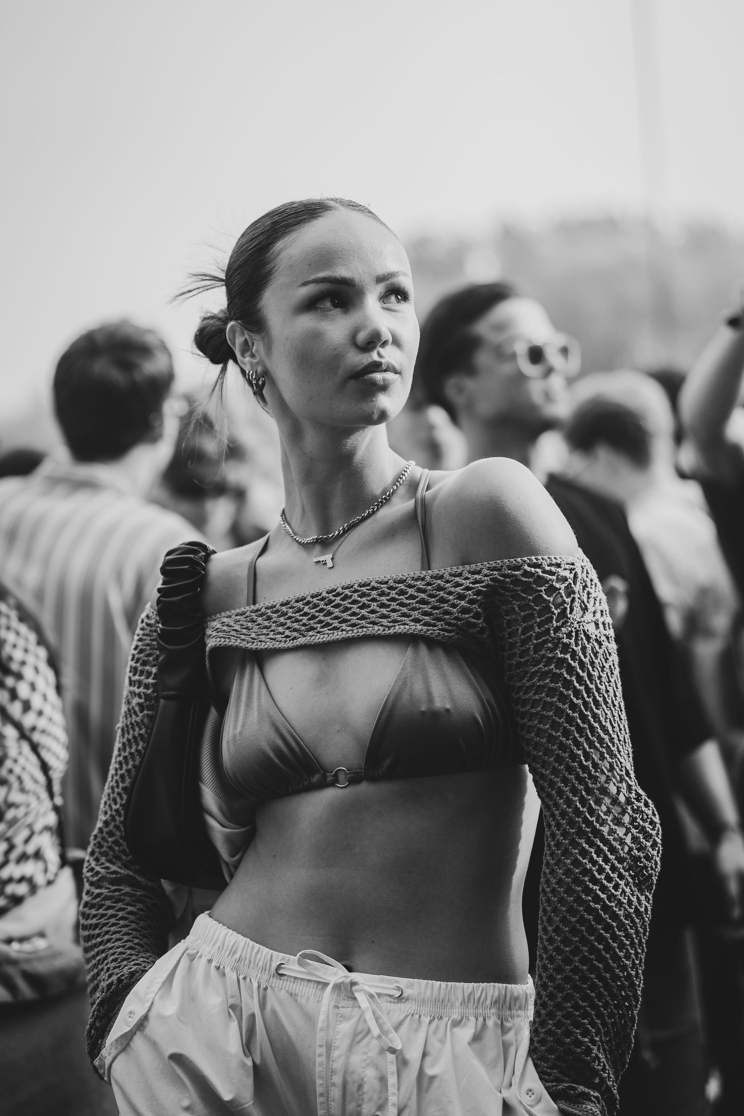 Black and white photo of a young woman in mesh top and bikini at an outdoor festival.