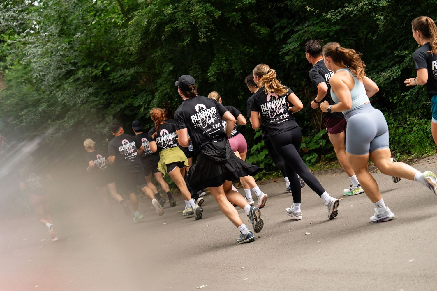 Group of runners jogging on a tree-lined path during an outdoor running event on a warm day.