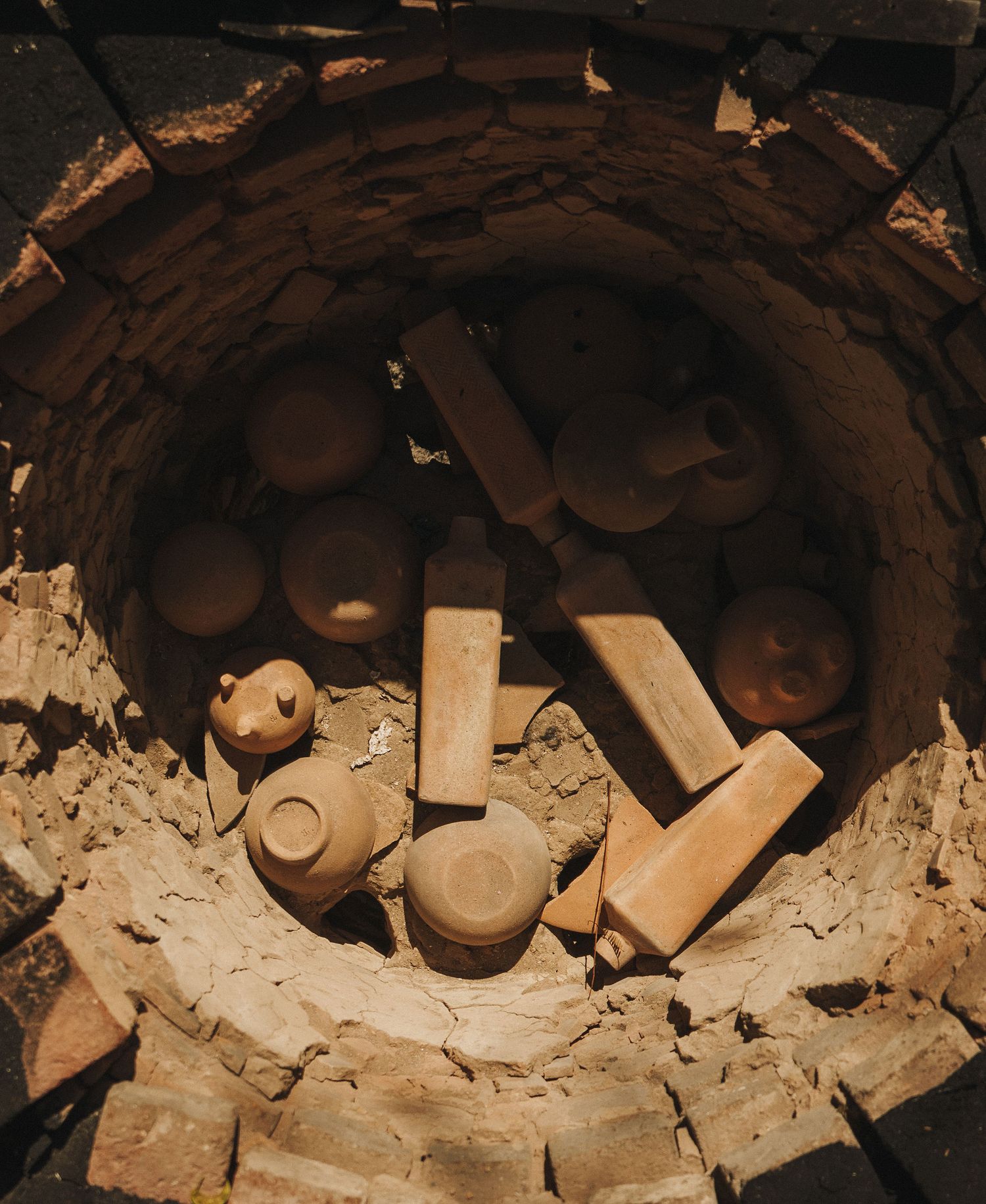 Aerial view of an ancient brick kiln filled with terracotta pottery and clay bricks in various stages of firing.