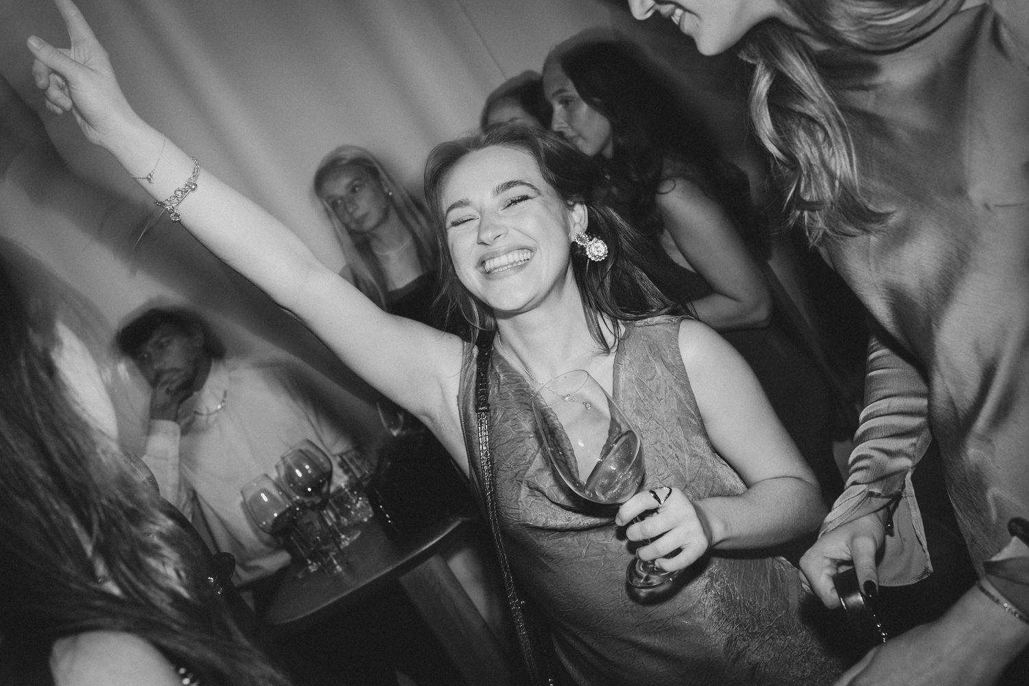 A joyful woman dances and raises her arm at a lively black and white party.