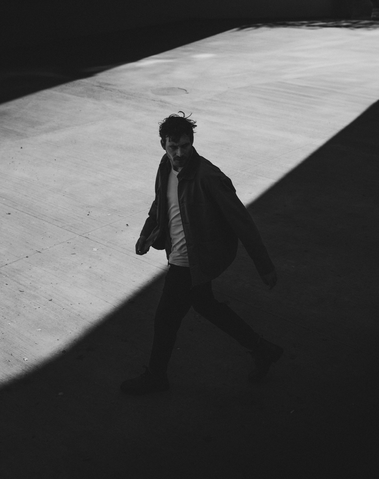 A dramatic black and white photo showing a person's silhouette casting a long shadow on a concrete floor.