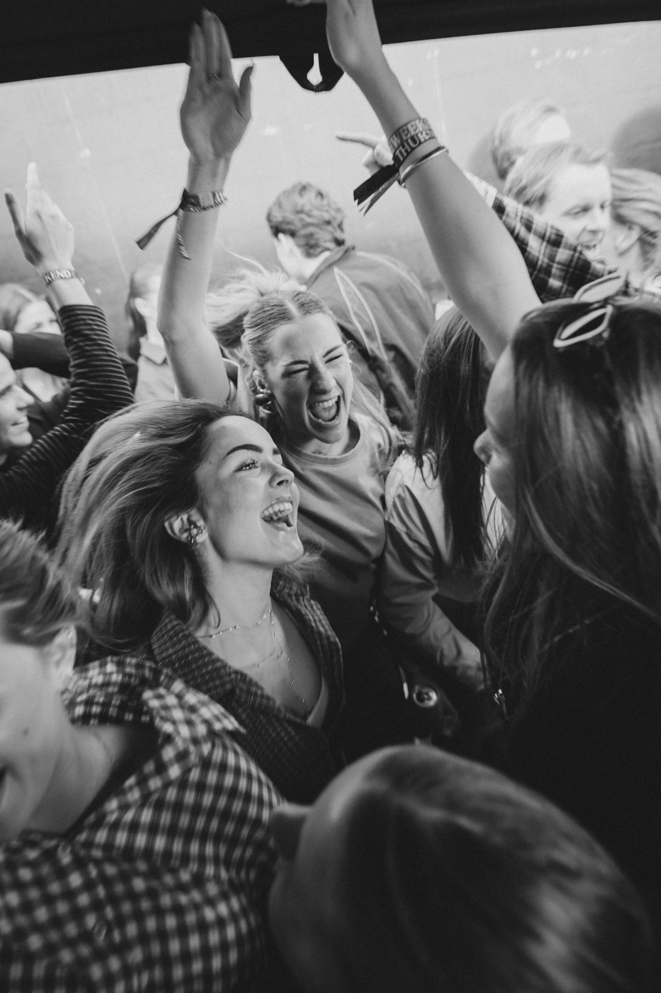 Black and white photo of joyful crowd dancing and celebrating at a lively party or concert event.