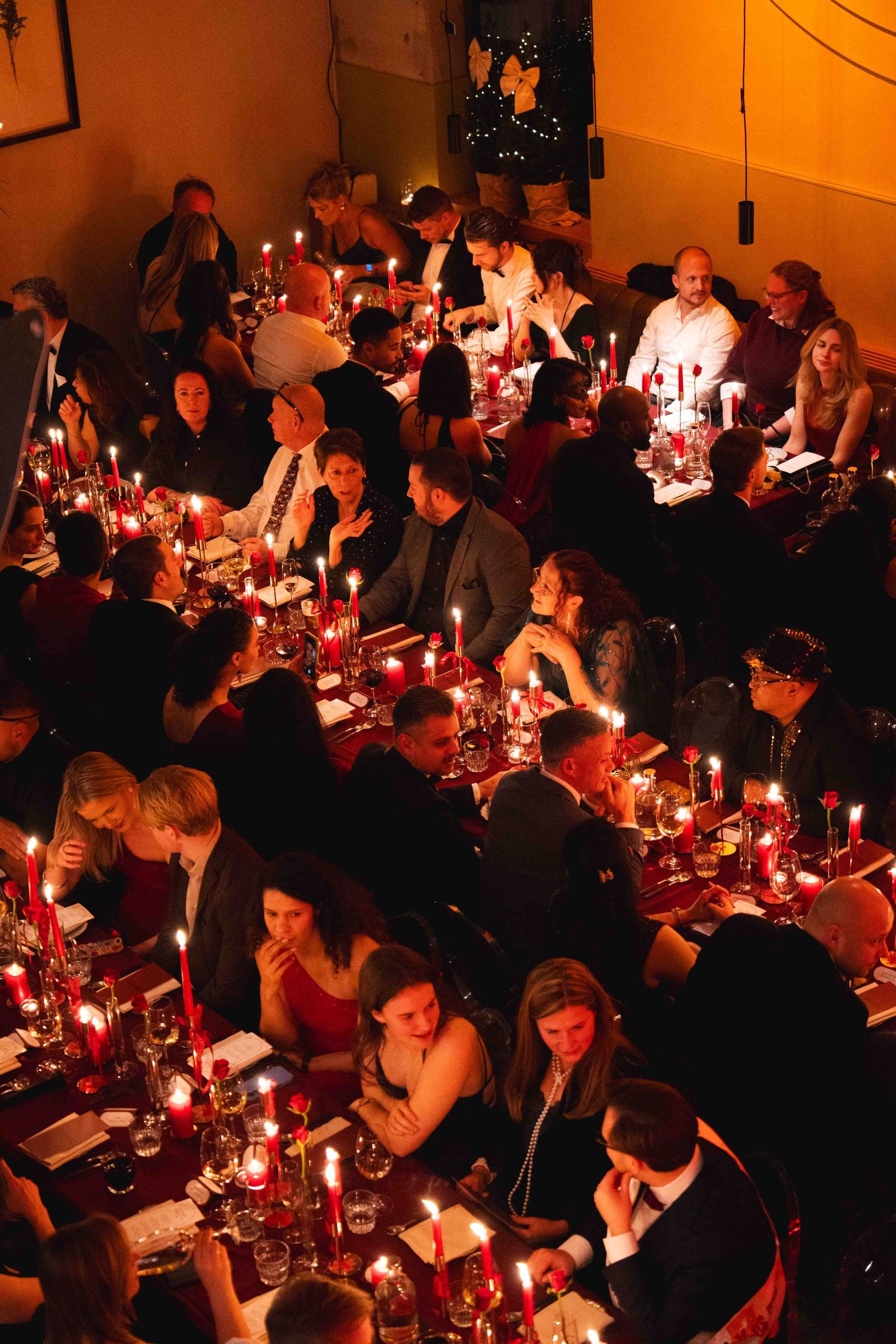 Guests dine by candlelight at long tables during an elegant evening event viewed from above.