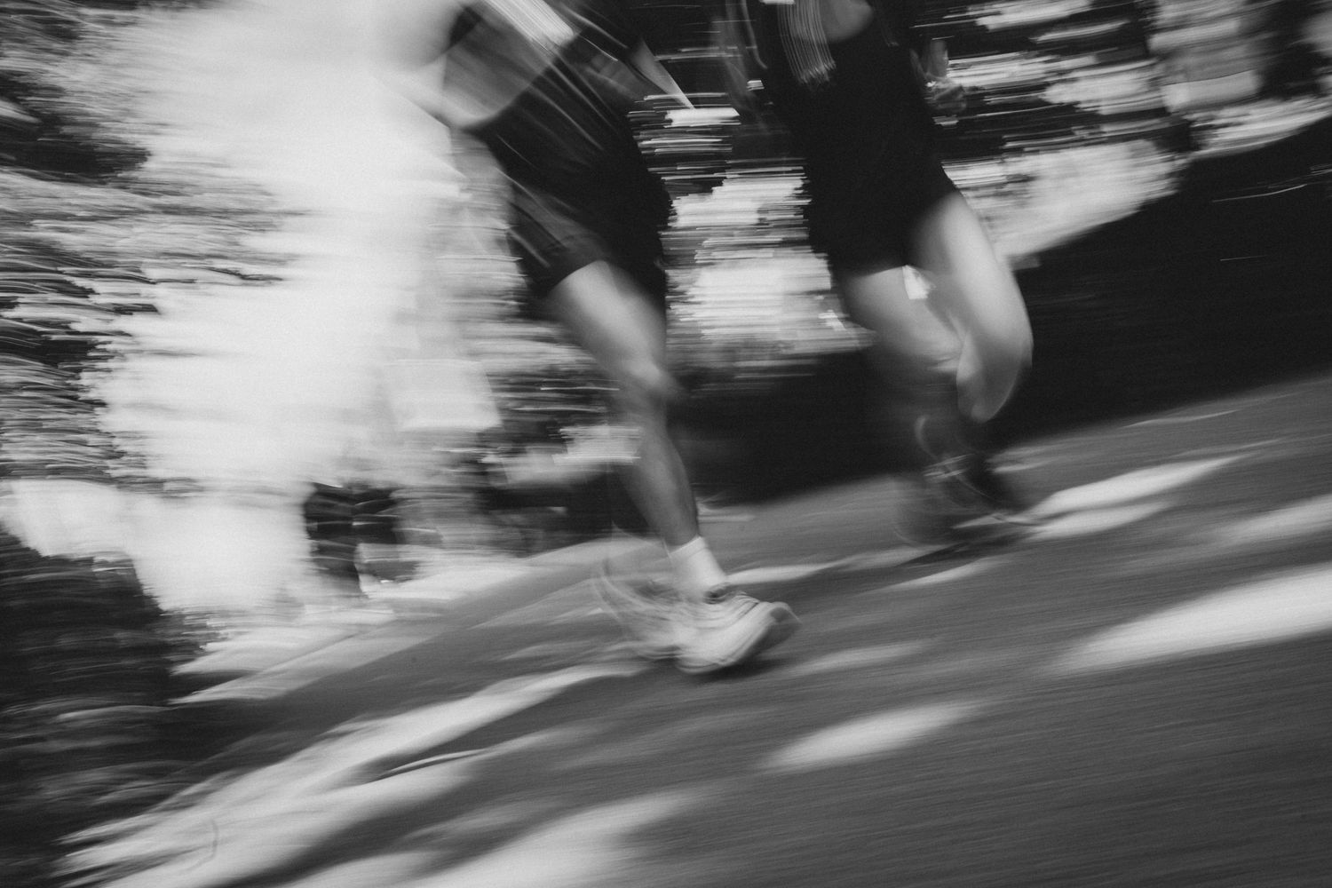 Blurred black and white photo of two runners in motion, capturing the speed and energy of a race.