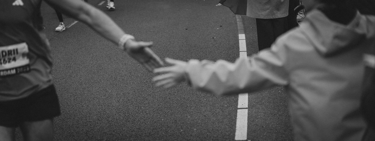 Black and white image of runners passing a water station during a race.