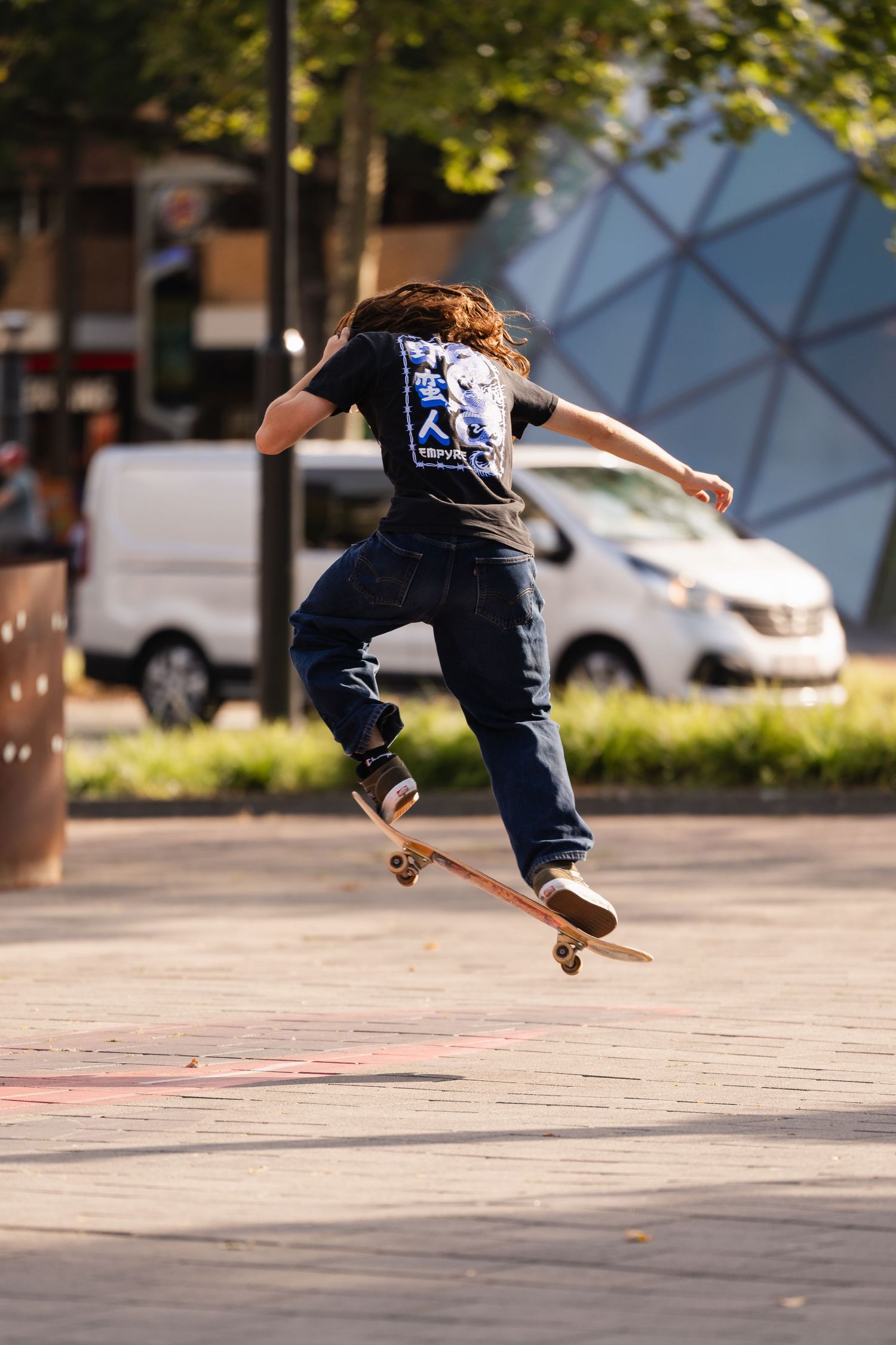 Skateboarder performing an ollie trick on a urban plaza street on a sunny day.