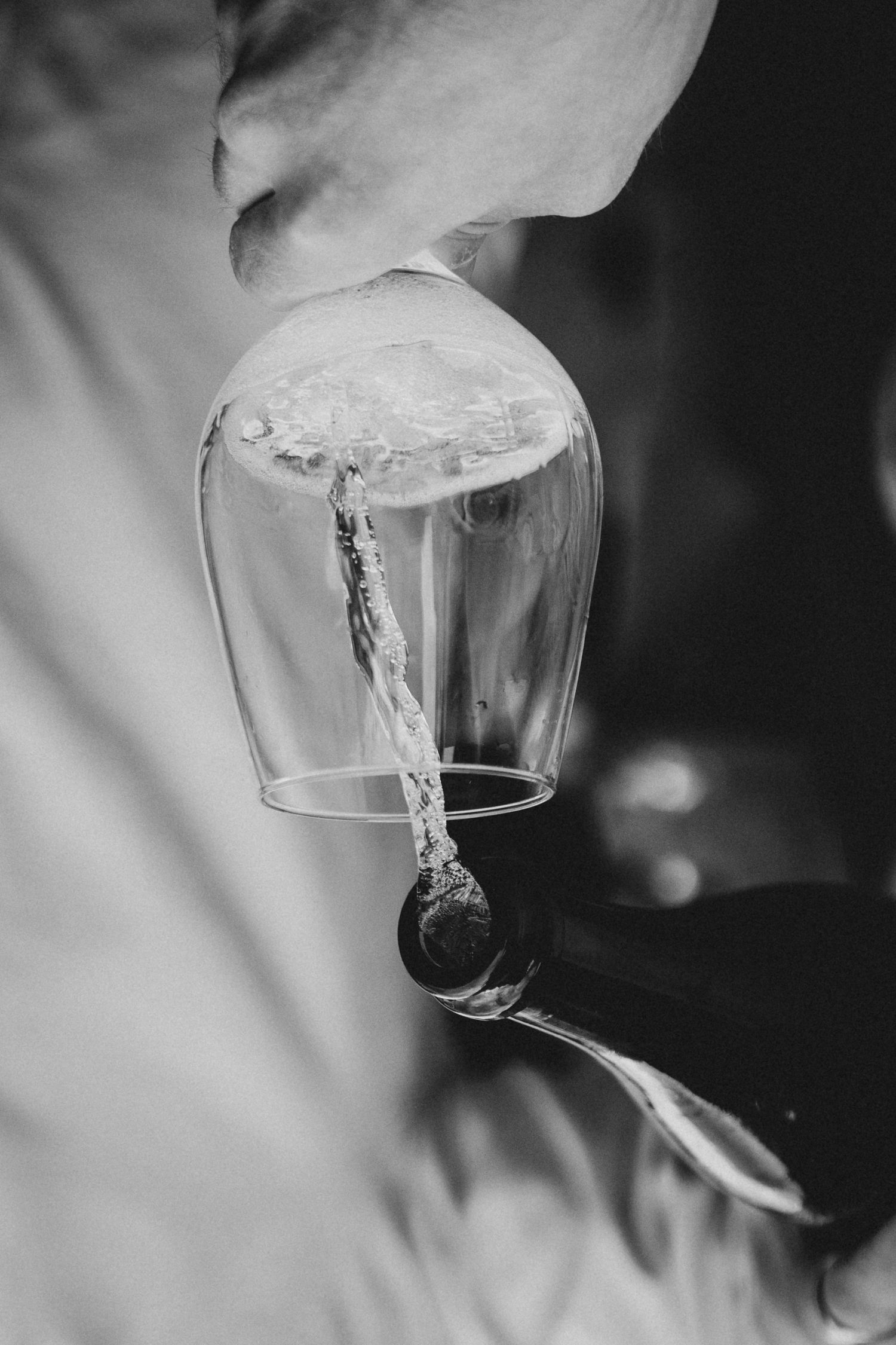 Black and white close-up of champagne being poured into an upside-down glass.