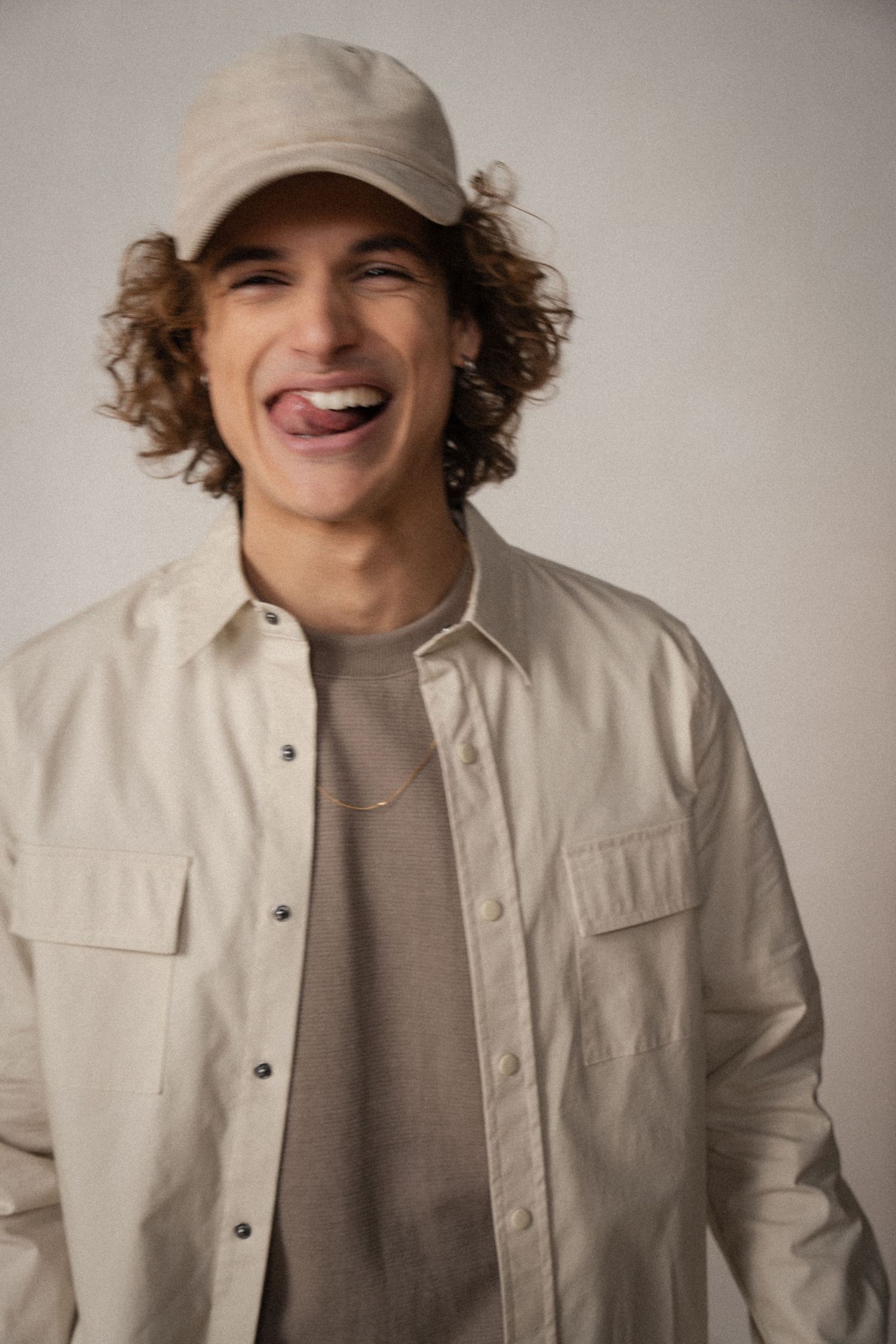 A series of five fashion portraits showing a person in a white button-up jacket and gray shirt against a neutral background.