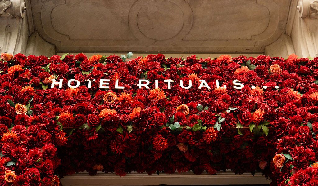 Lush red floral wall display with golden Hotel Rituals sign surrounded by vibrant red roses and flowers.