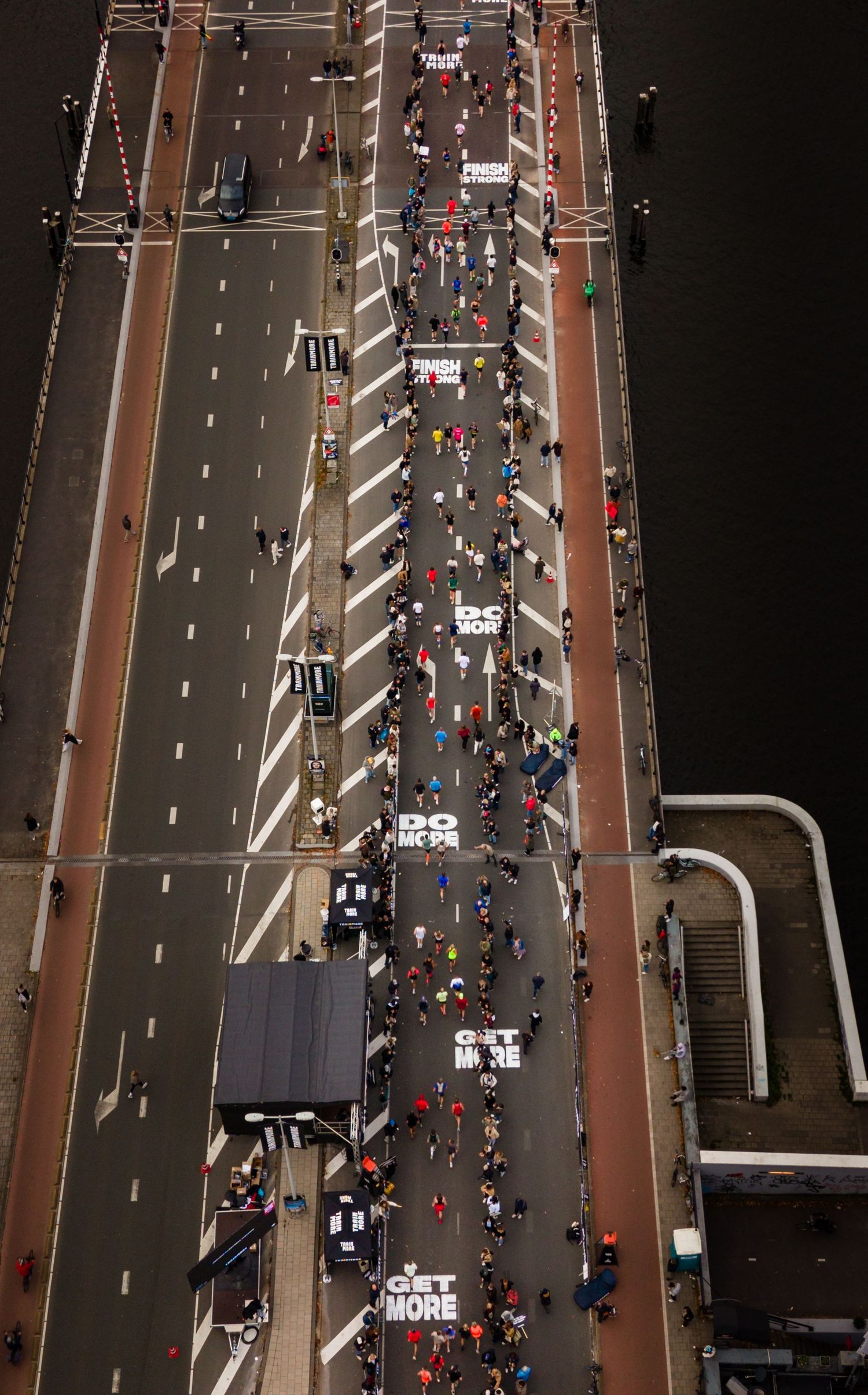 Aerial view of marathon runners crossing a bridge with traffic lanes.