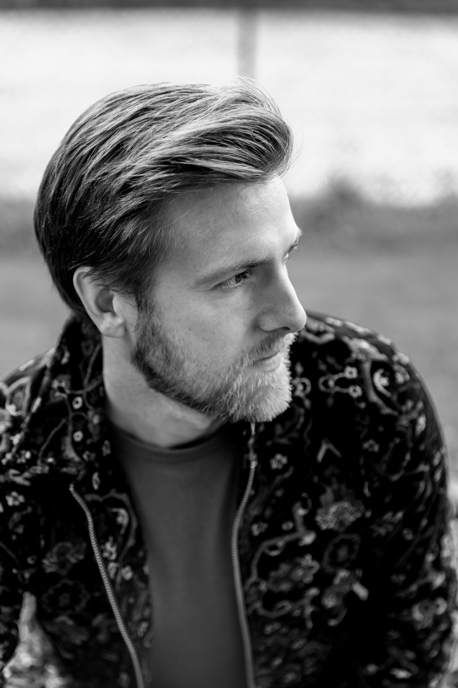 Profile view of someone wearing a patterned dark jacket in black and white.