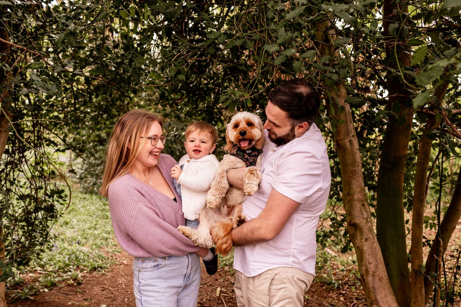 Family enjoying tender moment together in wooded outdoor setting.