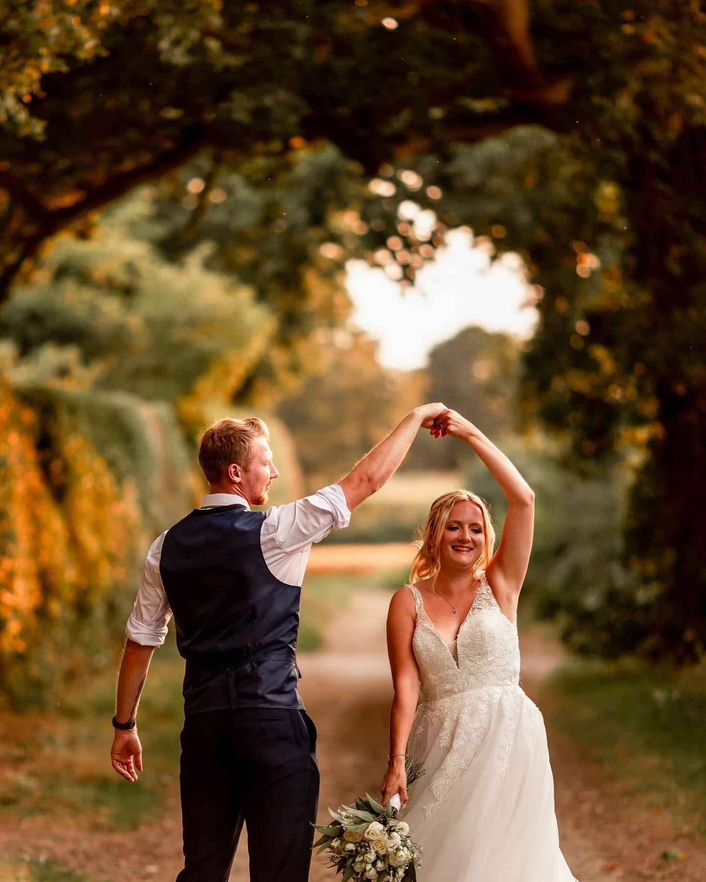 Newlyweds share playful dance moves during golden hour in outdoor garden setting.