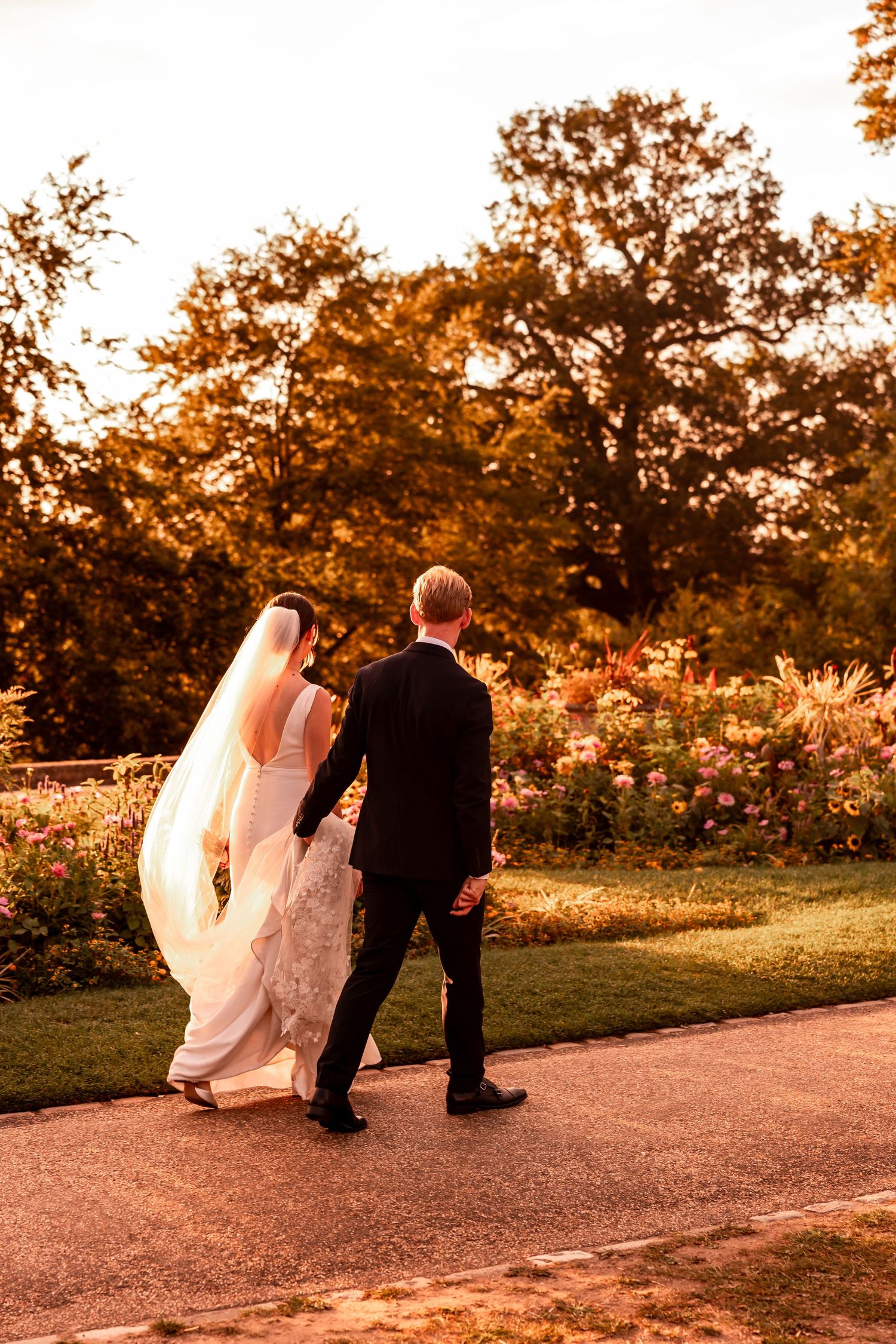 Couple walking along a sunset-lit path during their wedding photoshoot.