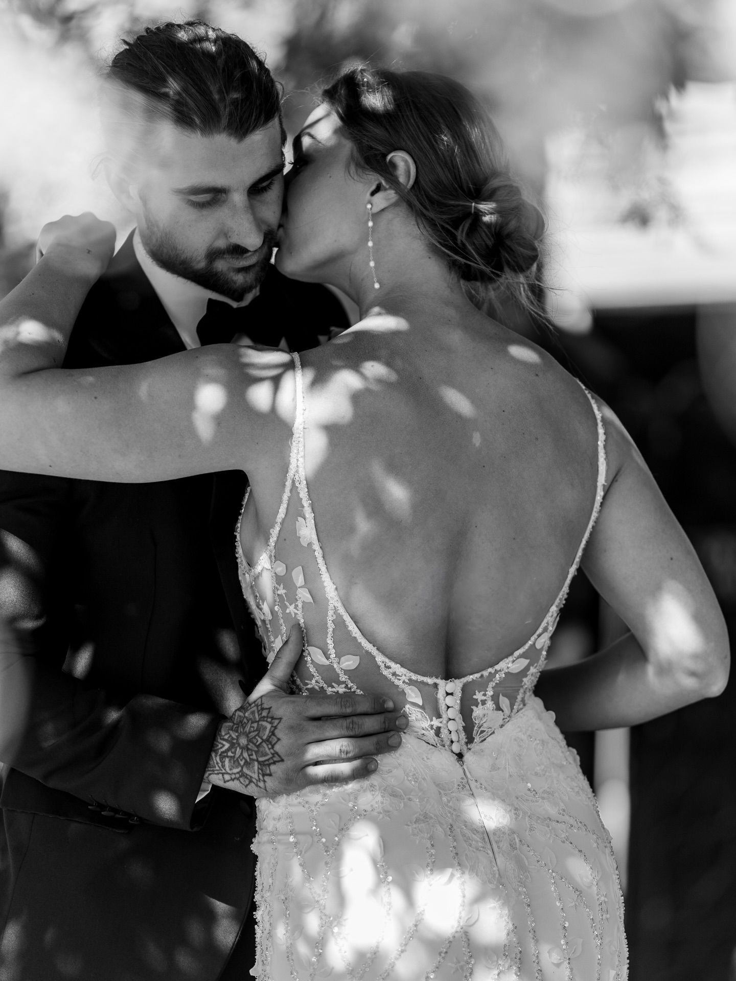 Black and white artistic wedding portrait with dappled light and lace details.