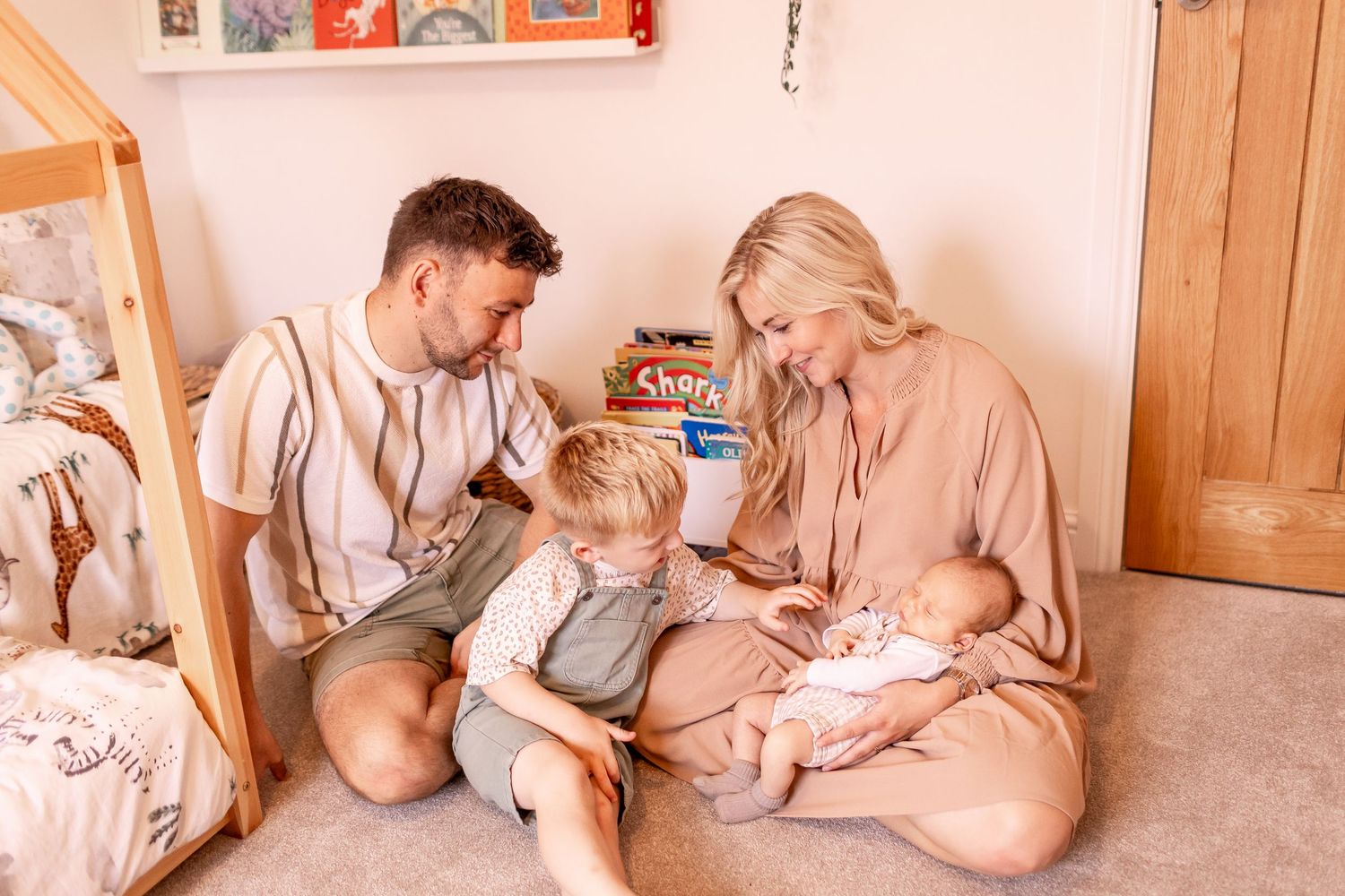 Warm-toned indoor photos capturing tender moments between an expecting couple on a comfortable sofa.