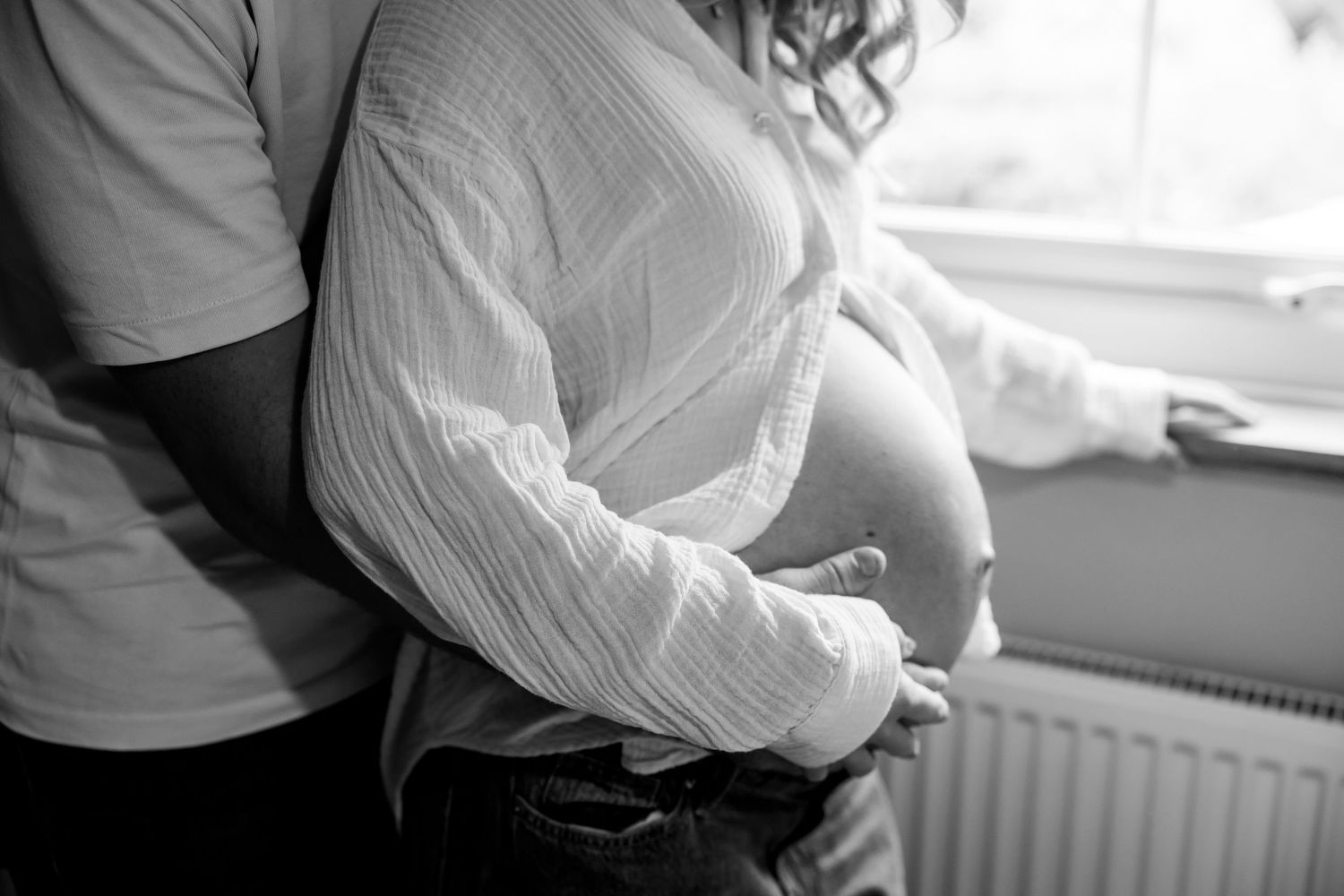 Intimate black and white maternity photos captured indoors with soft natural window light.