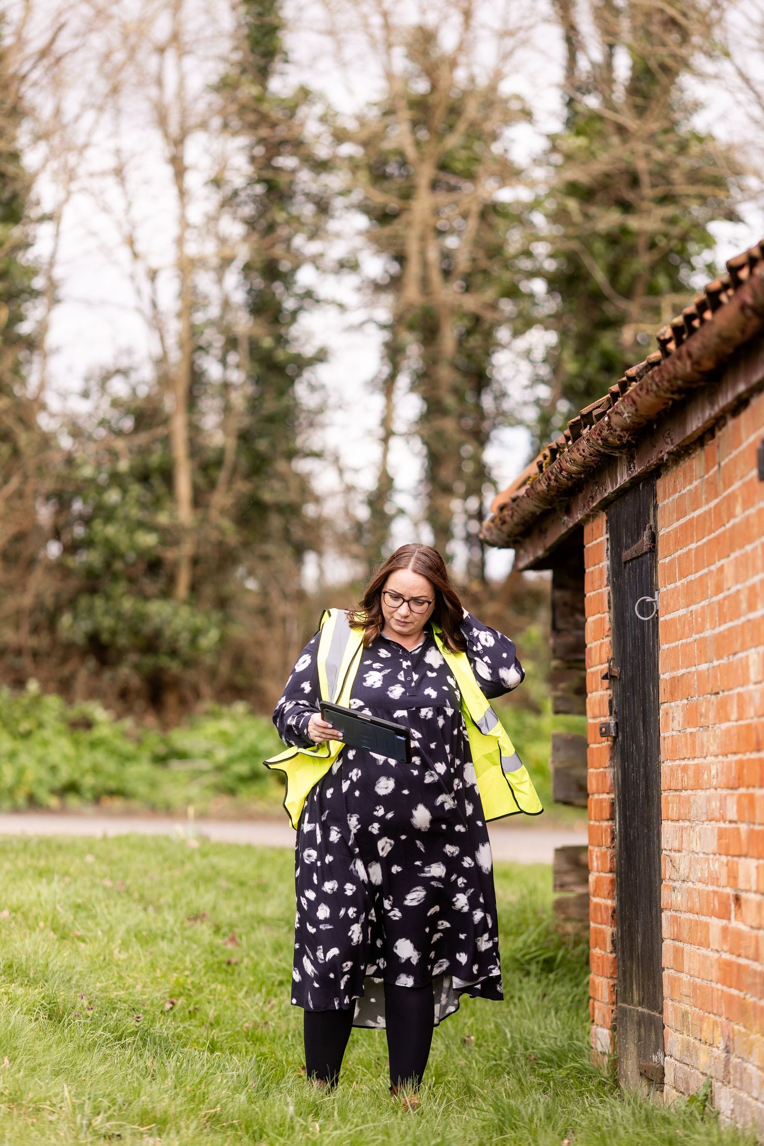 Outdoor portrait session against brick wall and green hillside.