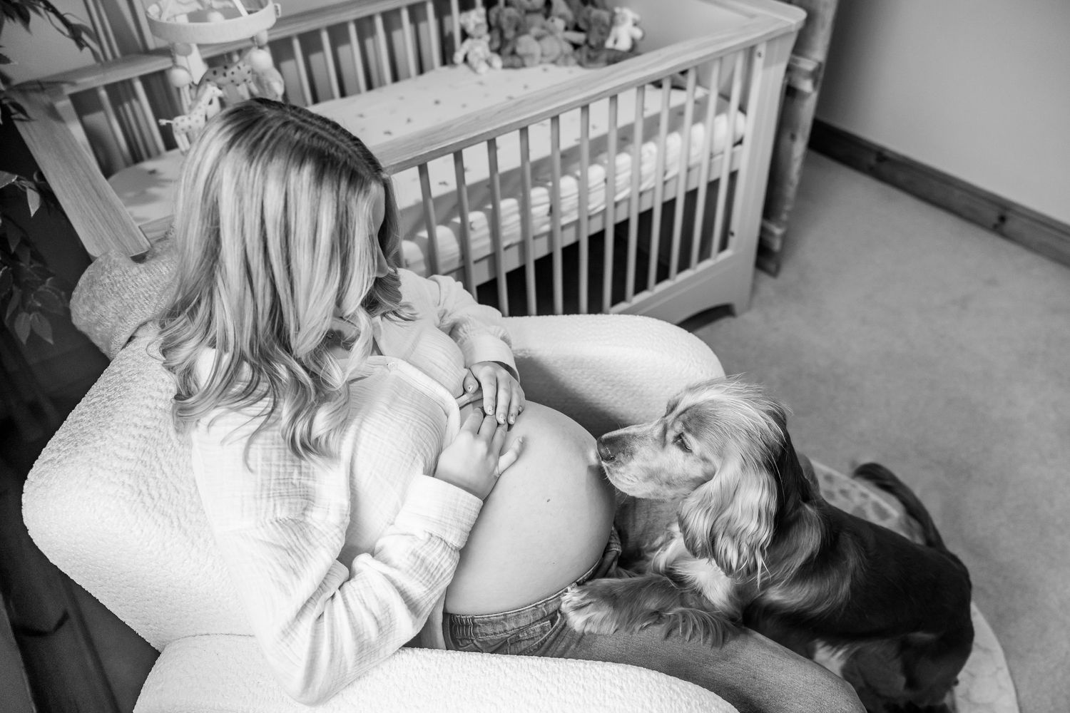 Black and white photos showing tender moments between parents and newborn in a nursery setting.