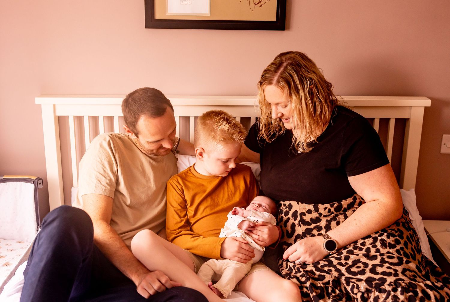 A family sharing a tender moment together on a bed while bonding with their baby.