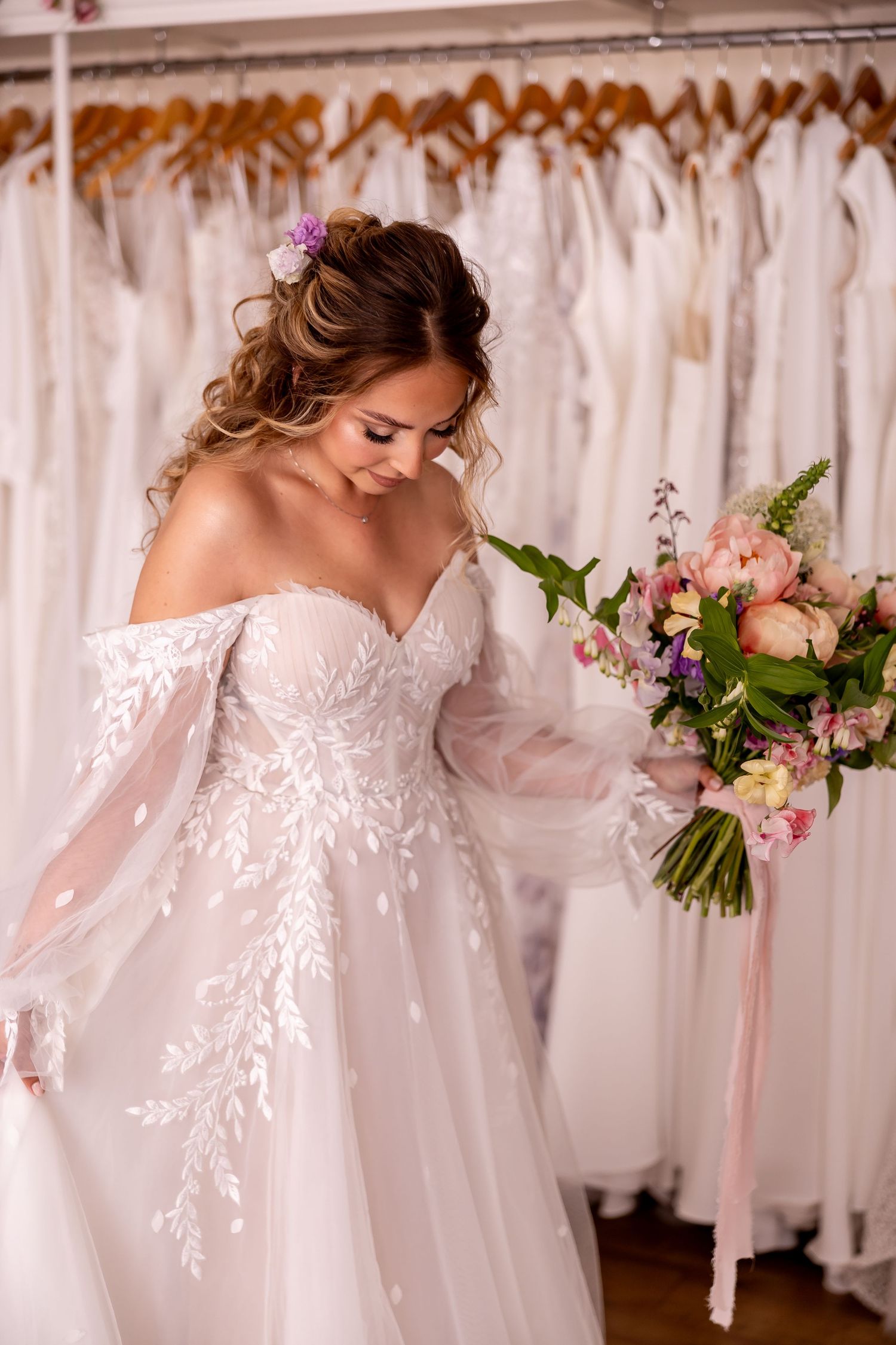 Delicate lace wedding gowns displayed in bridal boutique with soft lighting.