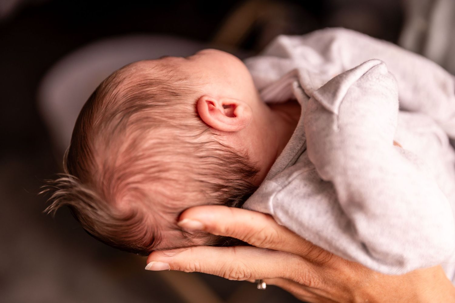 Gentle side view of sleeping newborn resting on soft surface.