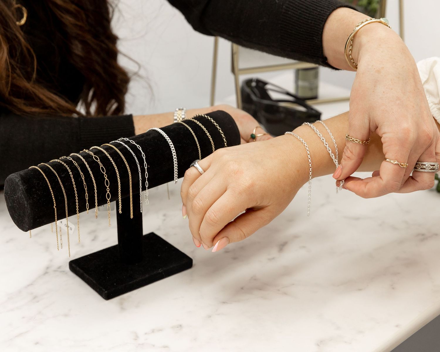 Close-up of hands organizing jewelry displays on white marble surface.